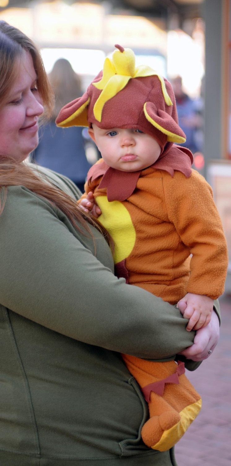 A mother celebrates the holiday with her baby boy, dressing him up as a monkey with a banana. 