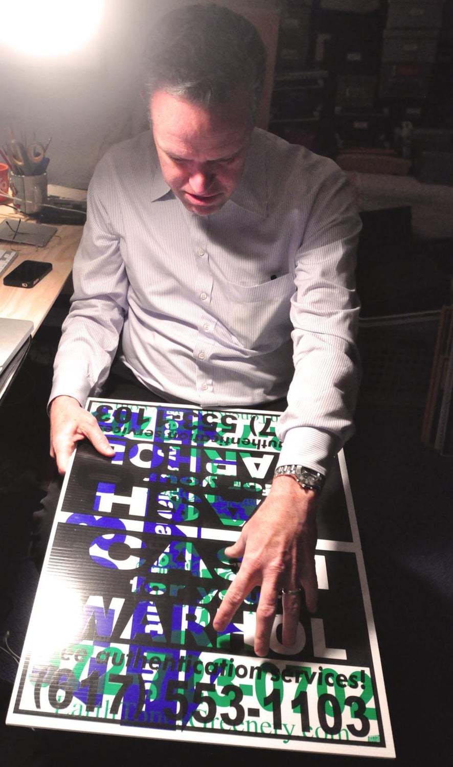 Geoff L. Hargadon ’76 holds a test print of one of the “Cash For Your Warhol” signs in his Somerville studio. 