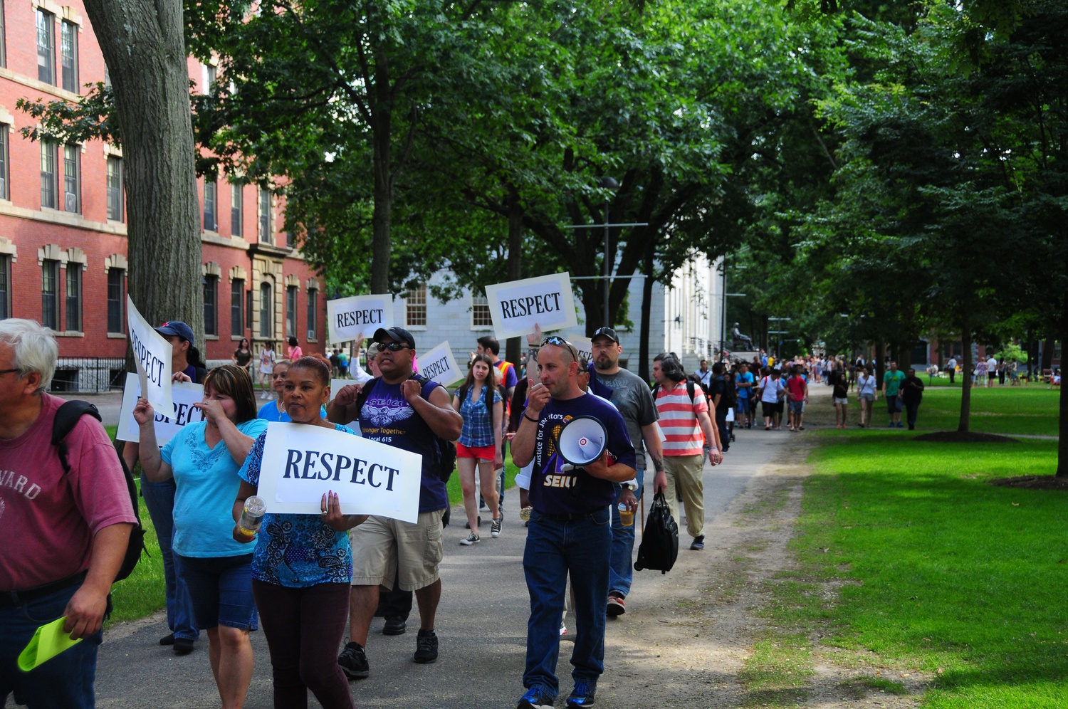 Workers, union members, and labor activists march through Harvard Yard on Wednesday afternoon in protest of Harvard Medical School's decision to cut 31 custodial contract jobs. Though the Medical School has cited financial constraints as reasoning behind the cuts, protesters alleged Wednesday that the terminations are unnecessary.