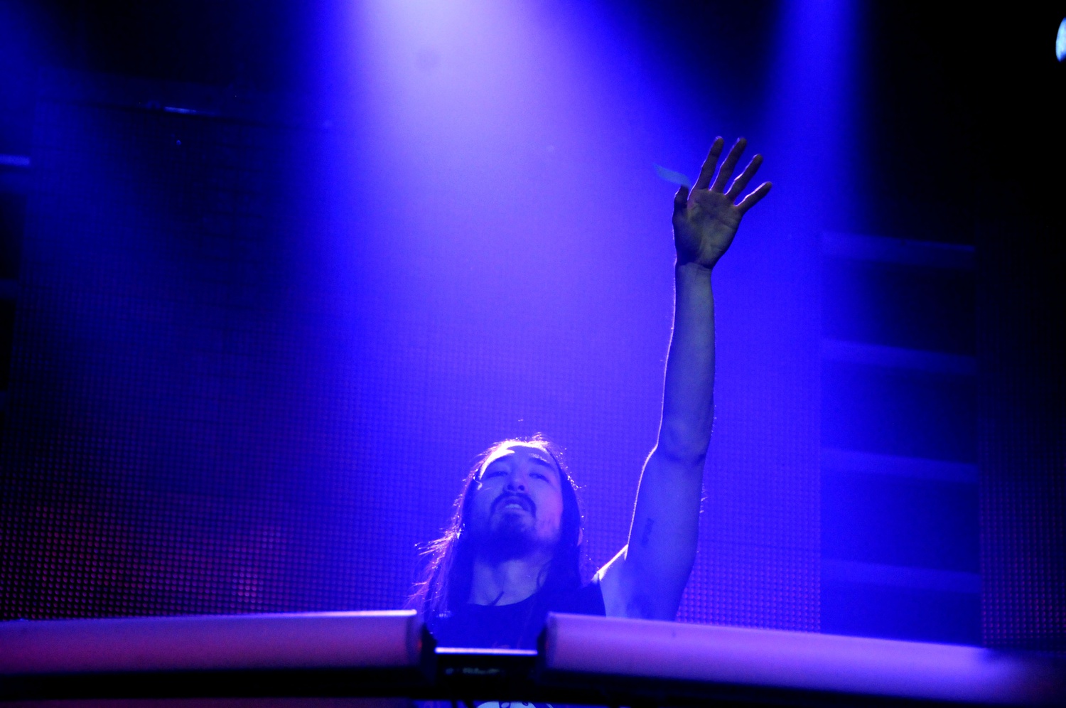 Steve Aoki waves to the crowd while mixing onstage during his performance. 