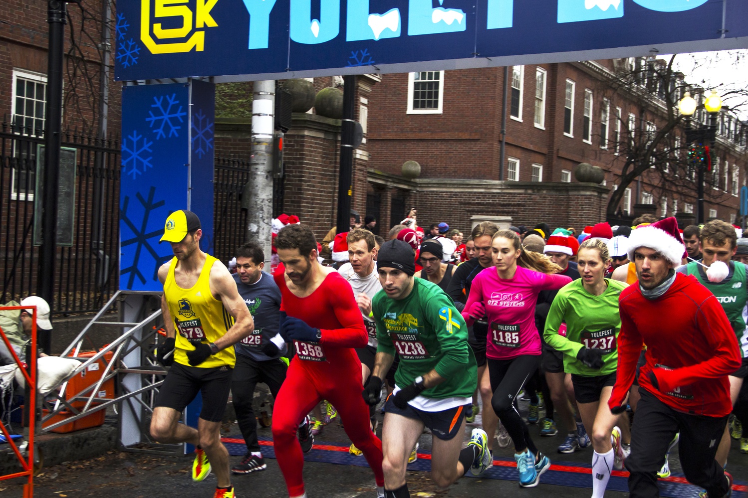 Runners are starting the 5K Yulefest race at the starting line on Massachusetts Avenue. The Yulefest race was a 5K run across Harvard Square in which participants were encouraged to wear holiday costumes.