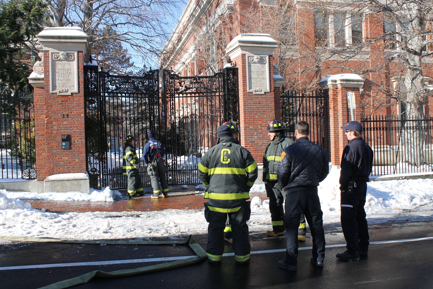 Firefighters stand outside the closed gates to Harvard Yard on Quincy St.