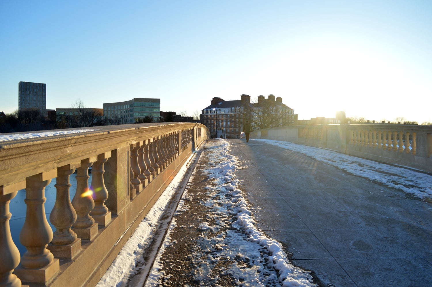 A pedestrian walks across the John W. Weeks bridge on a snowy afternoon. 