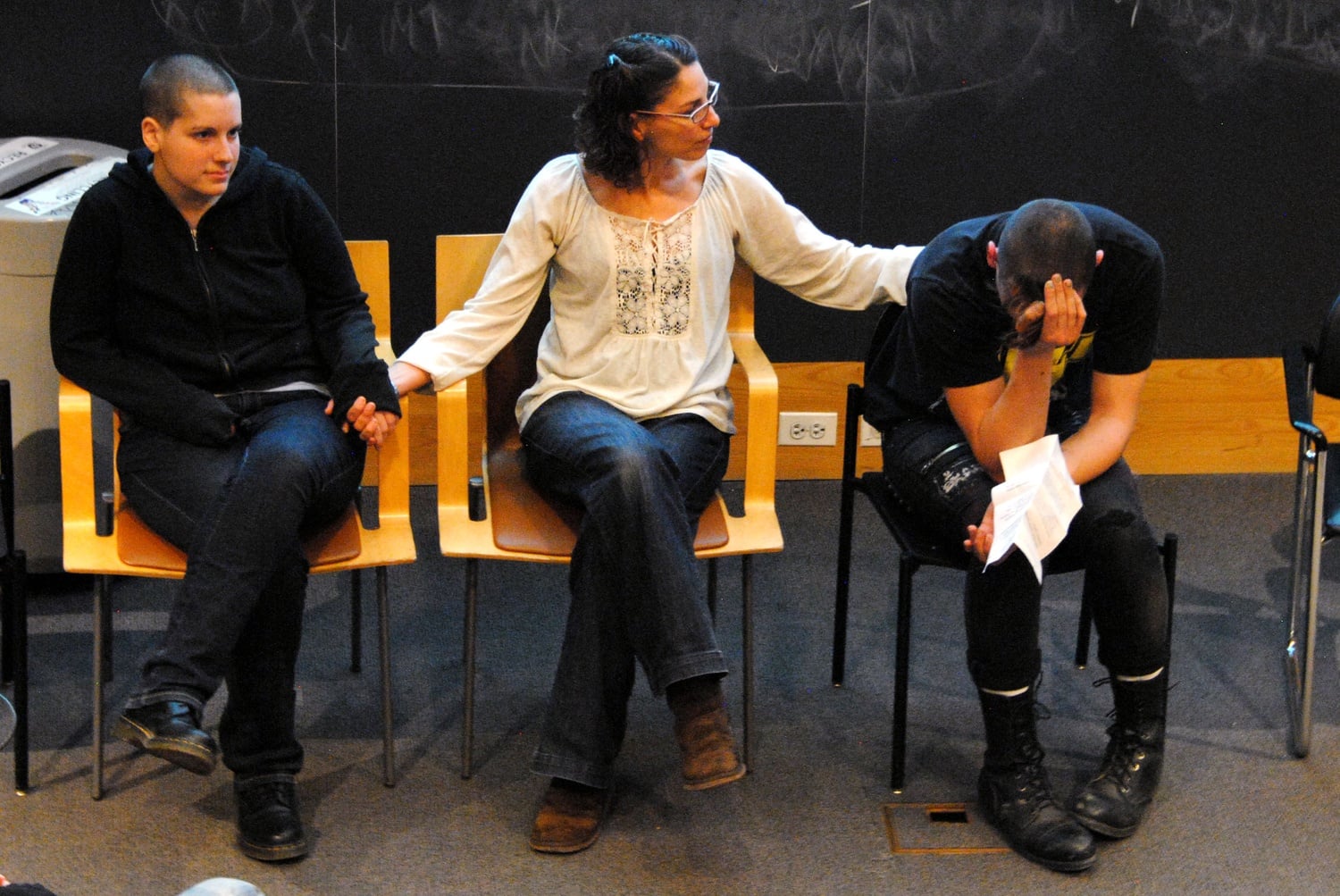 From left, Max, Ayala Livney, program manager for Youth On Fire, and Skyler listen emotionally to their friend Alec as he speaks to a packed Fong Auditorium on March 3. Being homeless for years, Max, Skyler, and Alec told their stories and spoke about the importance of Youth On Fire and youth homeless shelters. 