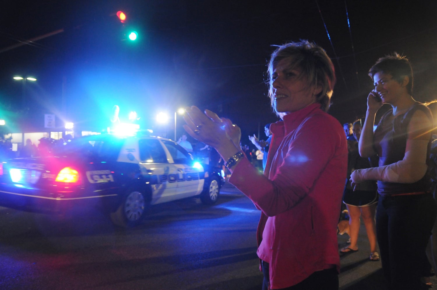An onlooker applauds as police units withdraw from the scene of Dzhokhar Tsarnaev’s capture in Watertown friday evening. Neighborhood residents lined Mt. Auburn St. to recognize emergency officials as they left the scene.
