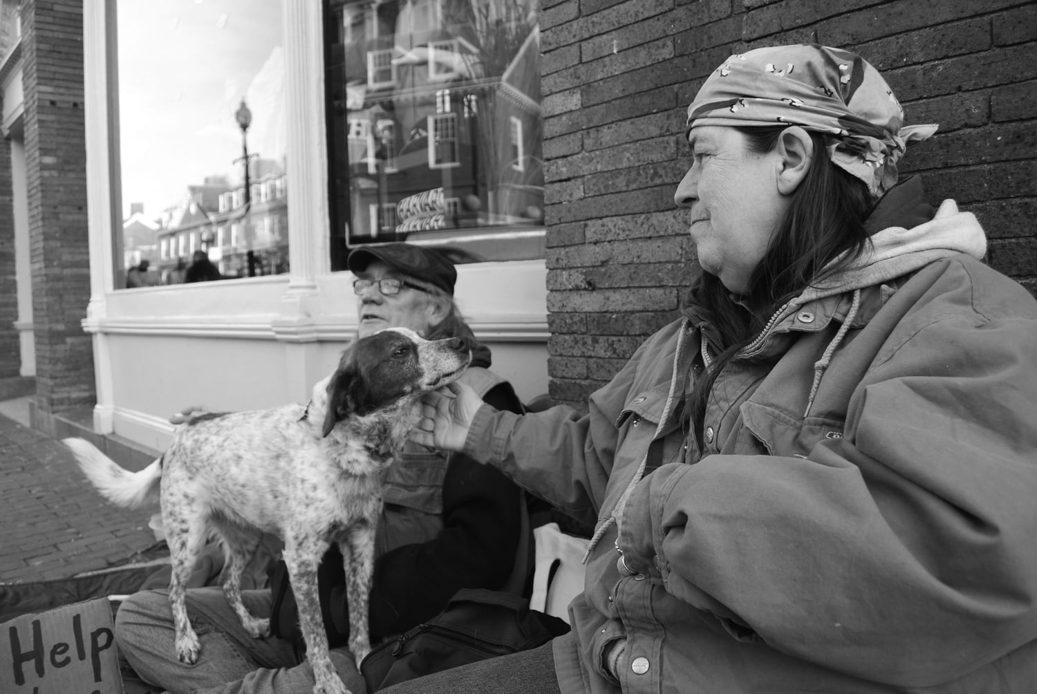 Earlene “Frenchie” French pets her dog Penny while panhandling with her partner, Ken O’Brien. O’Brien said that Penny is the second dog he has had while on the street, and that caring for a pet has motivated him to stay sober.