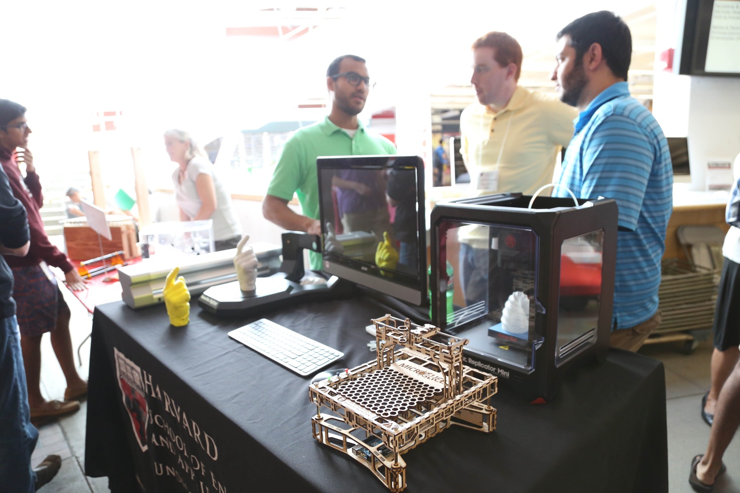 Representatives of the Undergraduate Teaching Labs at SEAS converse in front of engineering models at the Academic Fair in the Science Center in 2014.