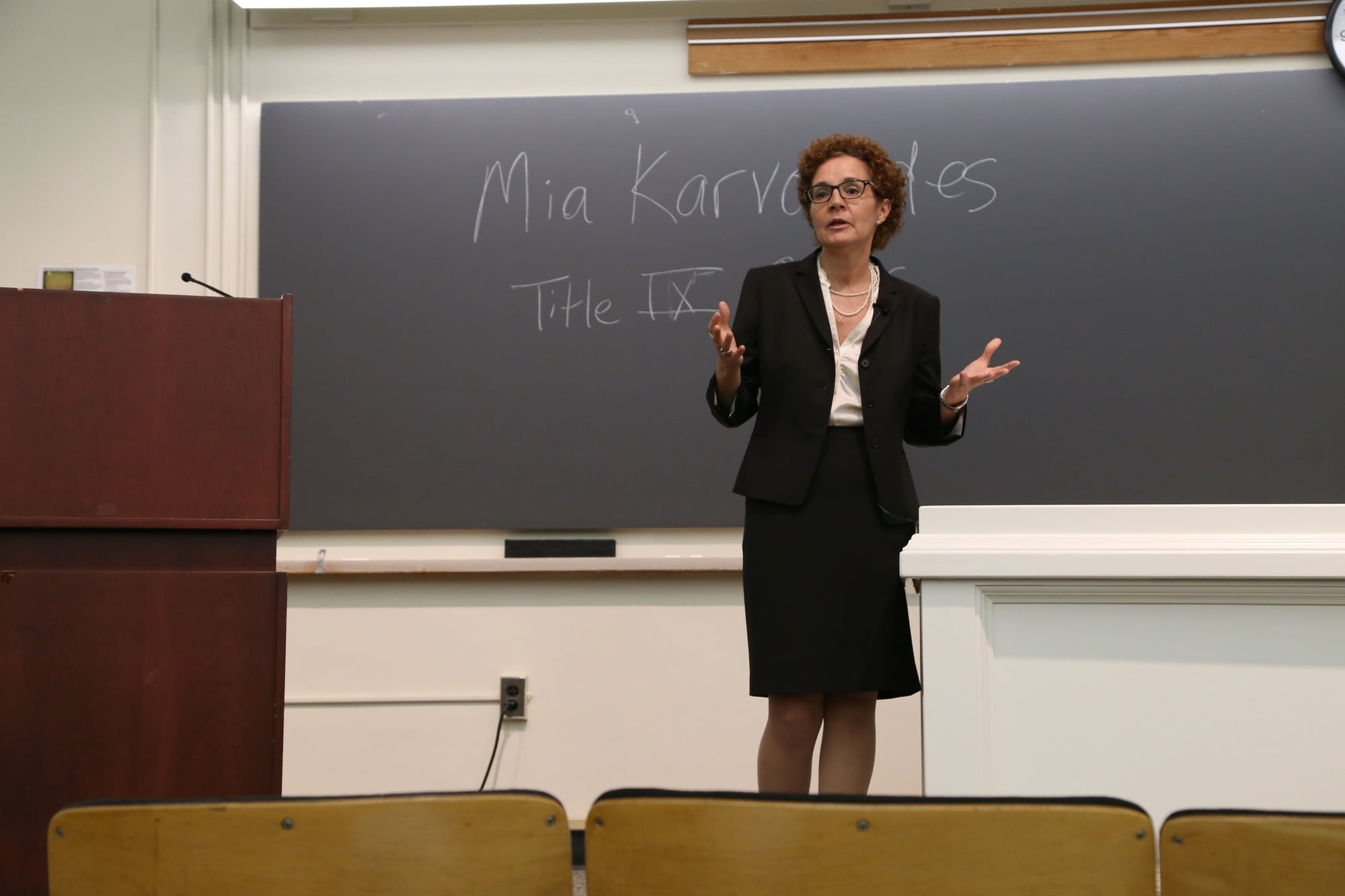 Members of the Harvard community watch as Mia Karvonides, Harvard's Title IX officer, speaks about Harvard's new sexual harassment policy and procedure on Tuesday evening. The community discussion, held in Emerson hall, was the first in a series of meetings on sexual harassment policy open to the Harvard community.