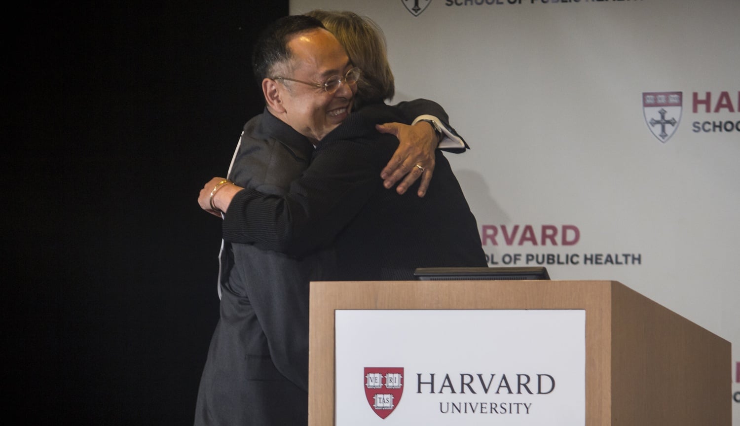 Gerald L. Chan, left, and University President Drew G. Faust embrace as Faust welcomes Chan on stage at the Harvard School of Public Health Monday afternoon for the unveiling of his foundation's $350 million gift.