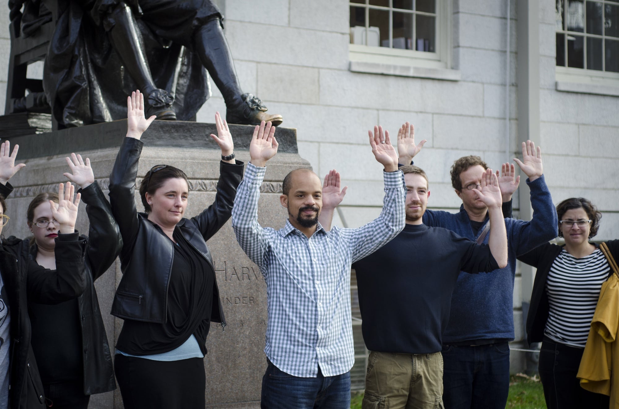 A group of protesters, mainly composed of Law School students, pose with their hands up in front of the John Harvard Statue on Monday afternoon to stand in solidarity with Ferguson protesters. 
