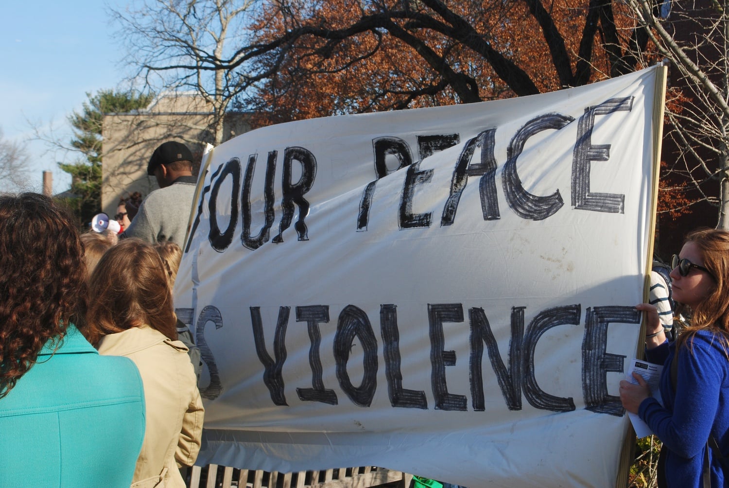A banner reads "Your Peace Is Violence." Protesters gathered from the Graduate School of Education and the  Law School for a rally on Monday at noon.