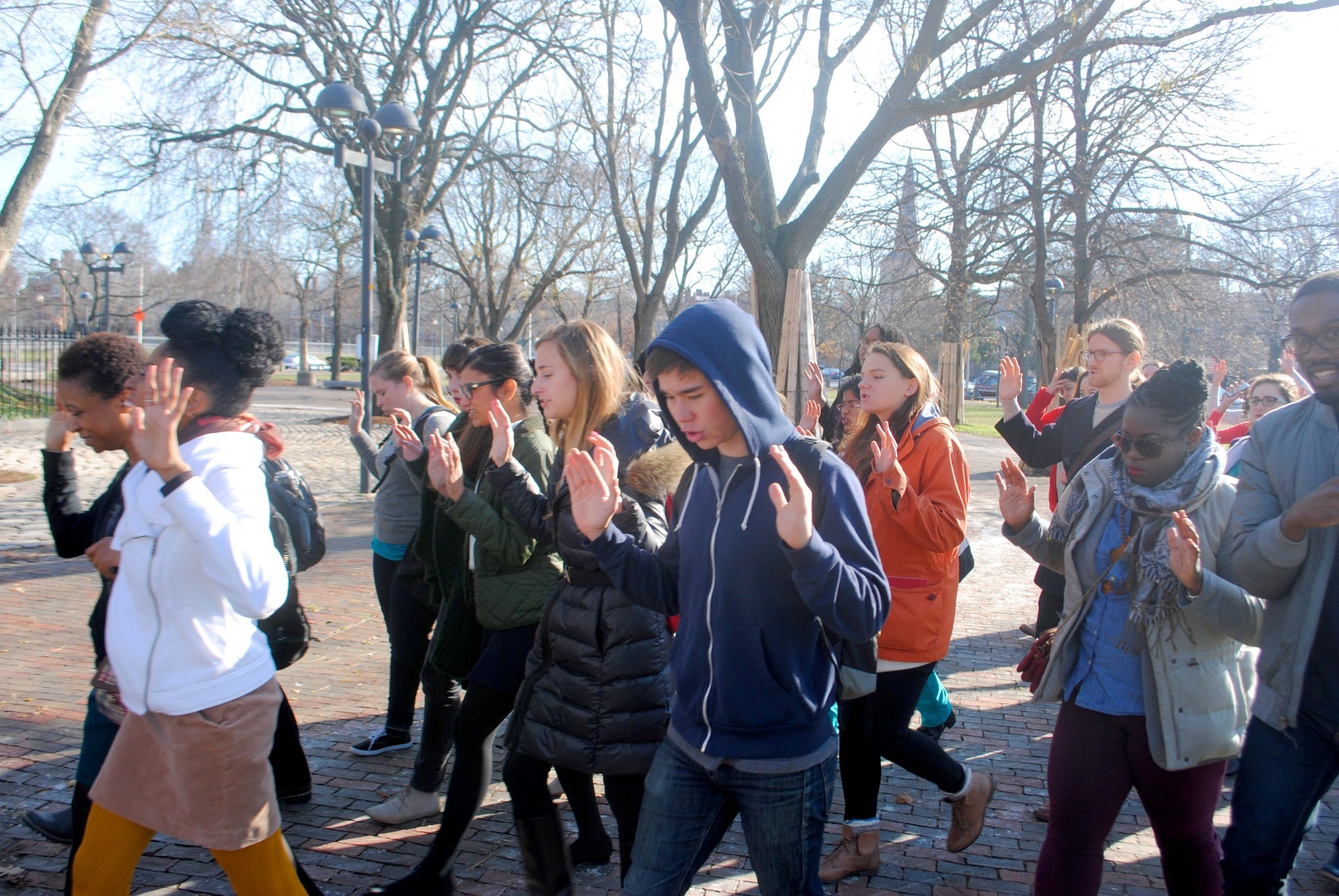 Protesters marching with their hands up from the Graduate School of Education to Harvard Law School in on Monday at noon.