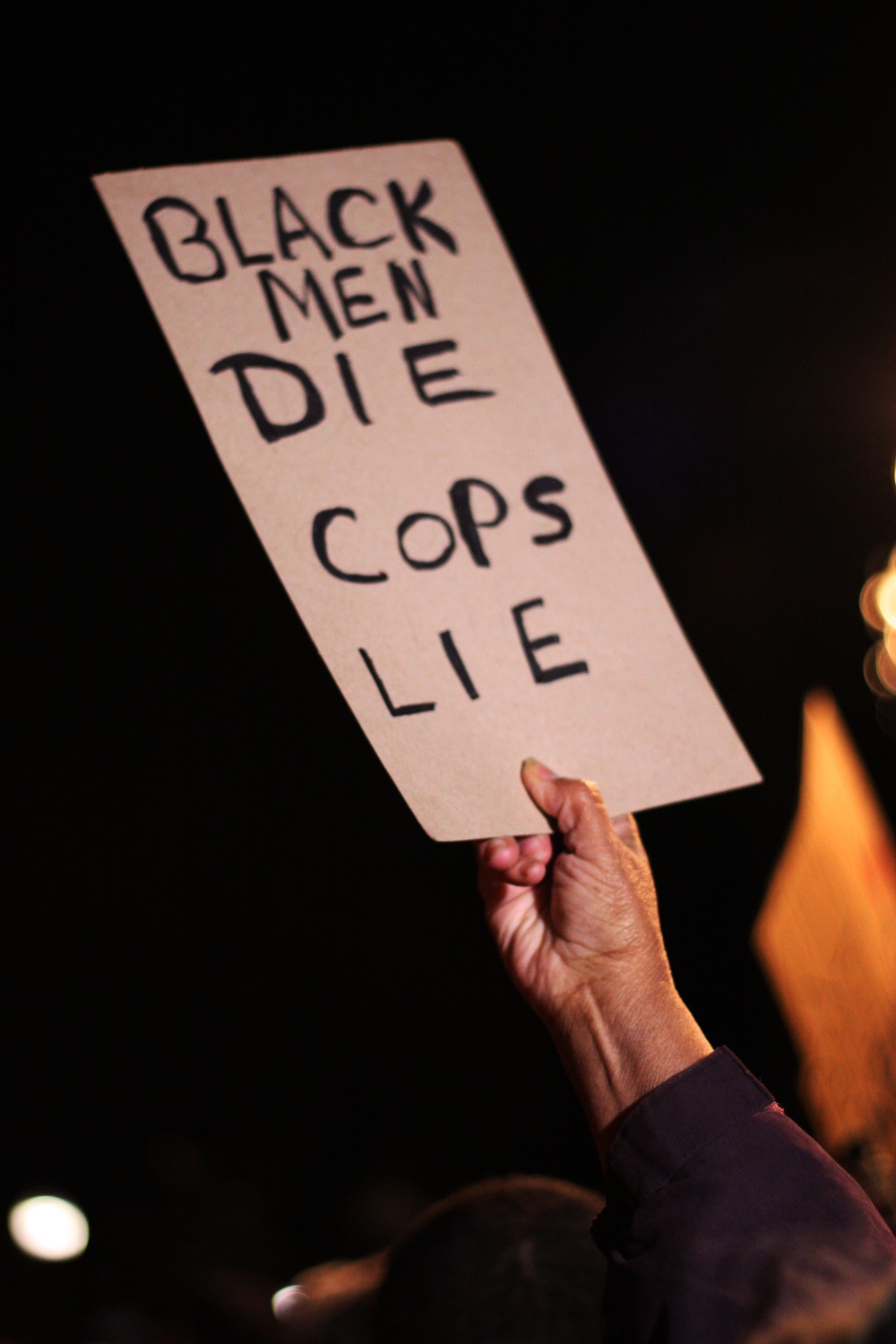 A protestor raises a sign at the Eric Garner protests in Boston Common on Thursday evening.