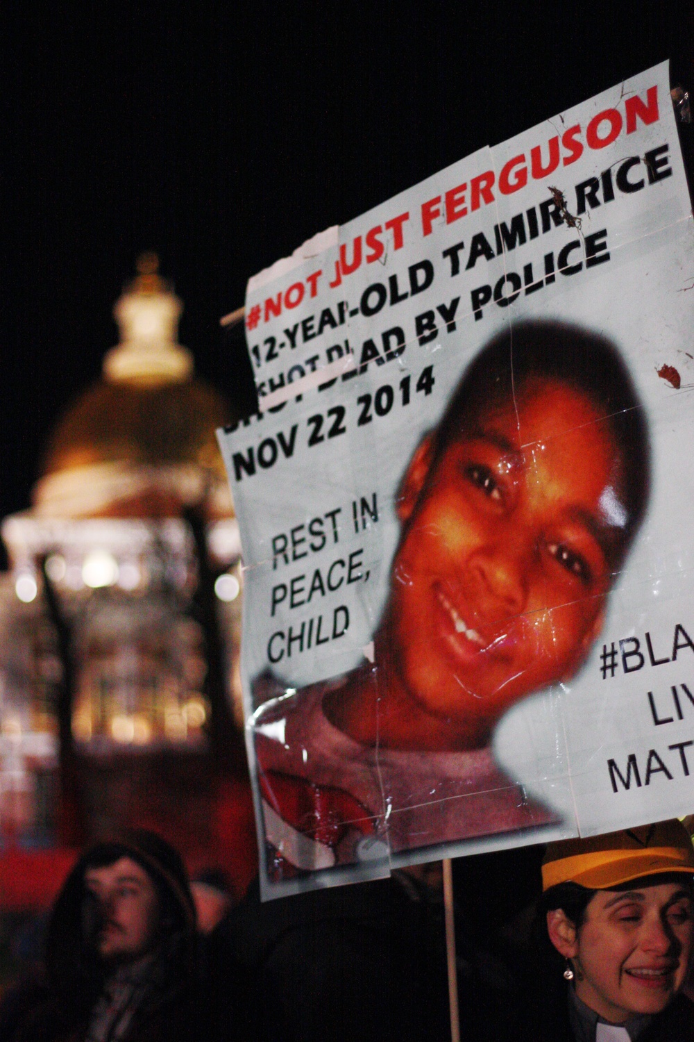 A protestor raises her sign in memory of Tamir Rice.