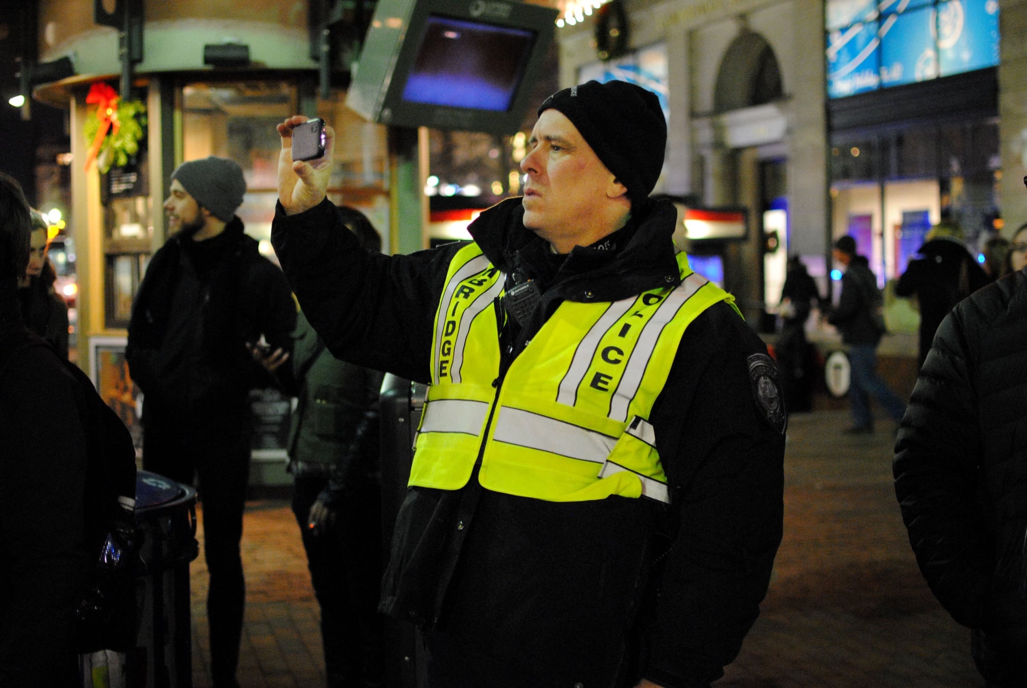 A Cambridge Police officer takes a photograph on his cellphone during a 'die in' in Harvard Square on Friday evening. 