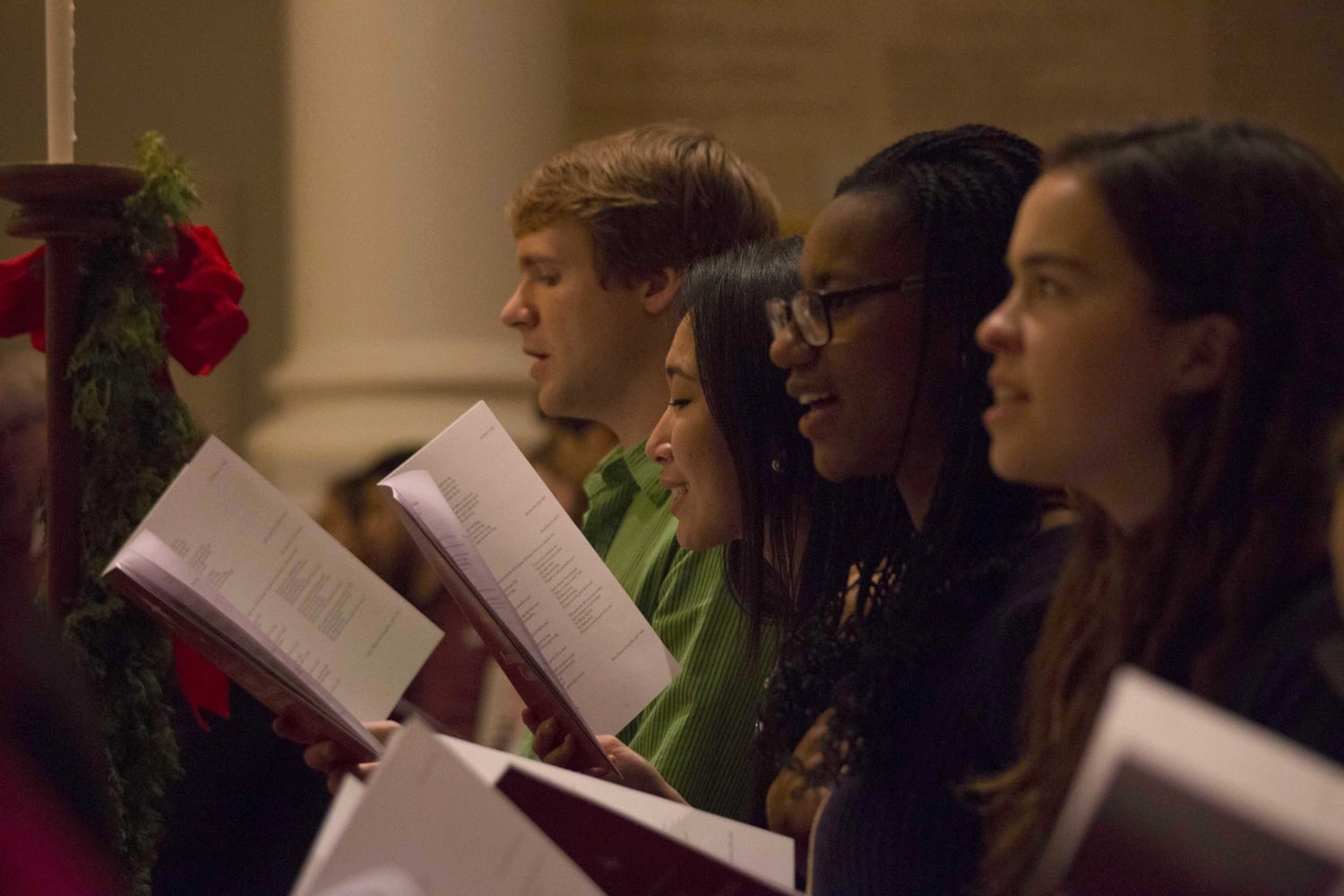 From left, MJ Richardson '17, Chloe B. Do '15, Karen-Alexandra Nogues '18, and Sarah C. Angell '18 sing along during the 105th Annual Christmas Carol Service in Memorial Church on Monday evening.