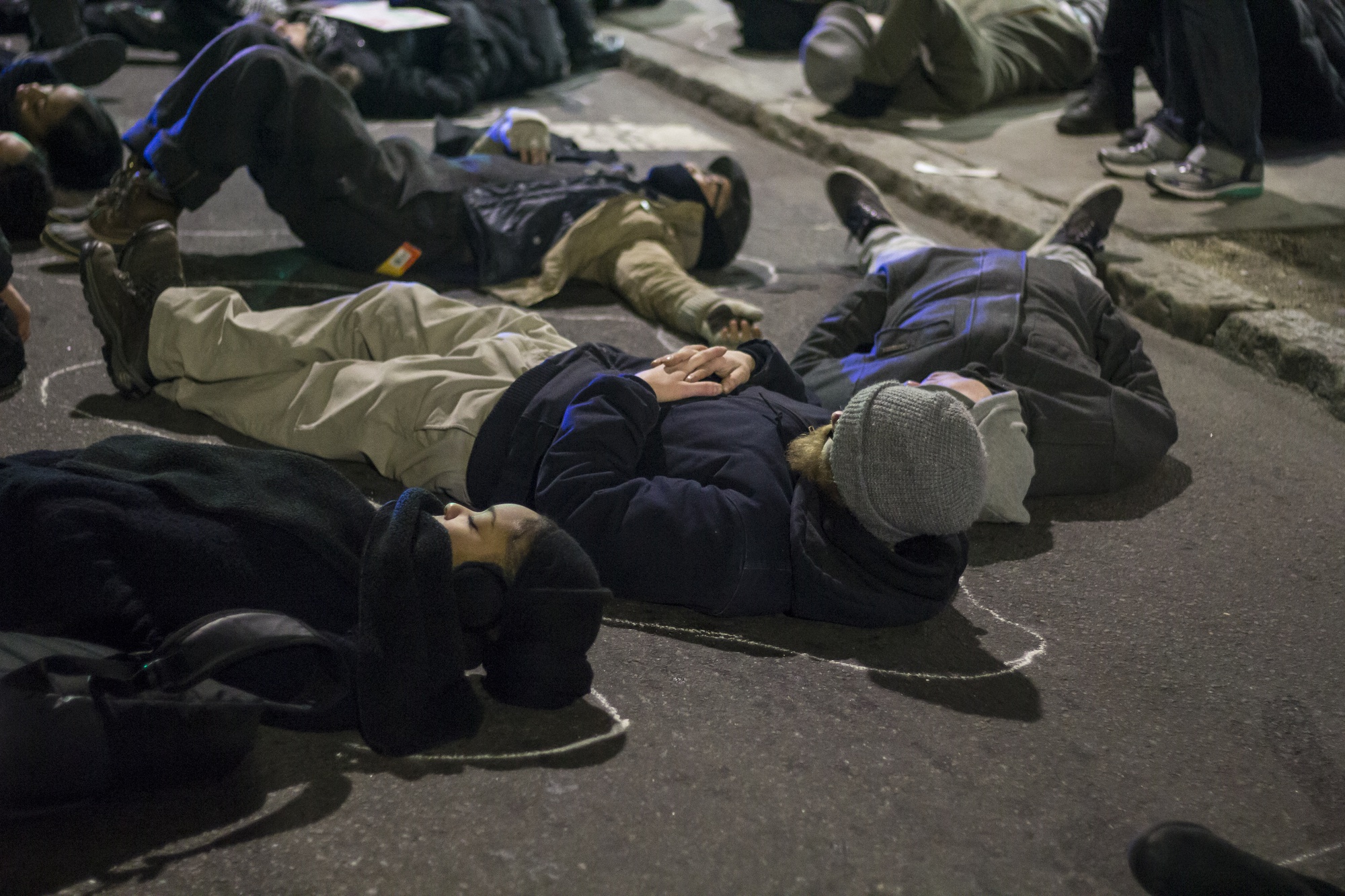 Protest participants lay in the street after having chalk outlines drawn around their bodies during a second die-in during a protest in Cambridge on Wednesday evening. The chalk alludes to the outline law enforcement officers traced around Michael Brown's body.