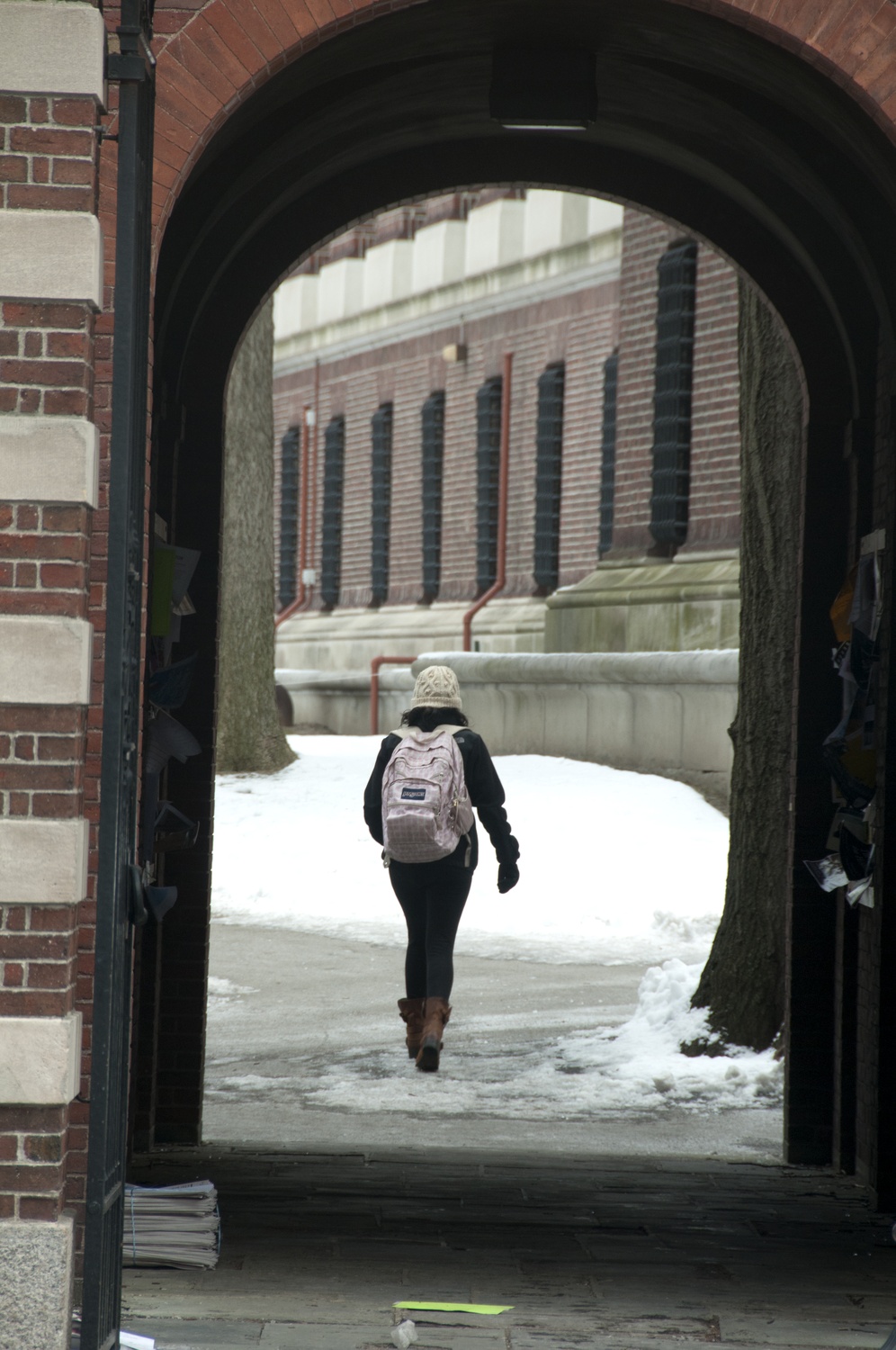 A student makes her way to class Monday, ducking under an archway near Widener Library. In anticipation of a looming and "potentially historic" snowstorm, administrators canceled Tuesday class after students had gotten a taste of classes during the first day of shopping week Monday.