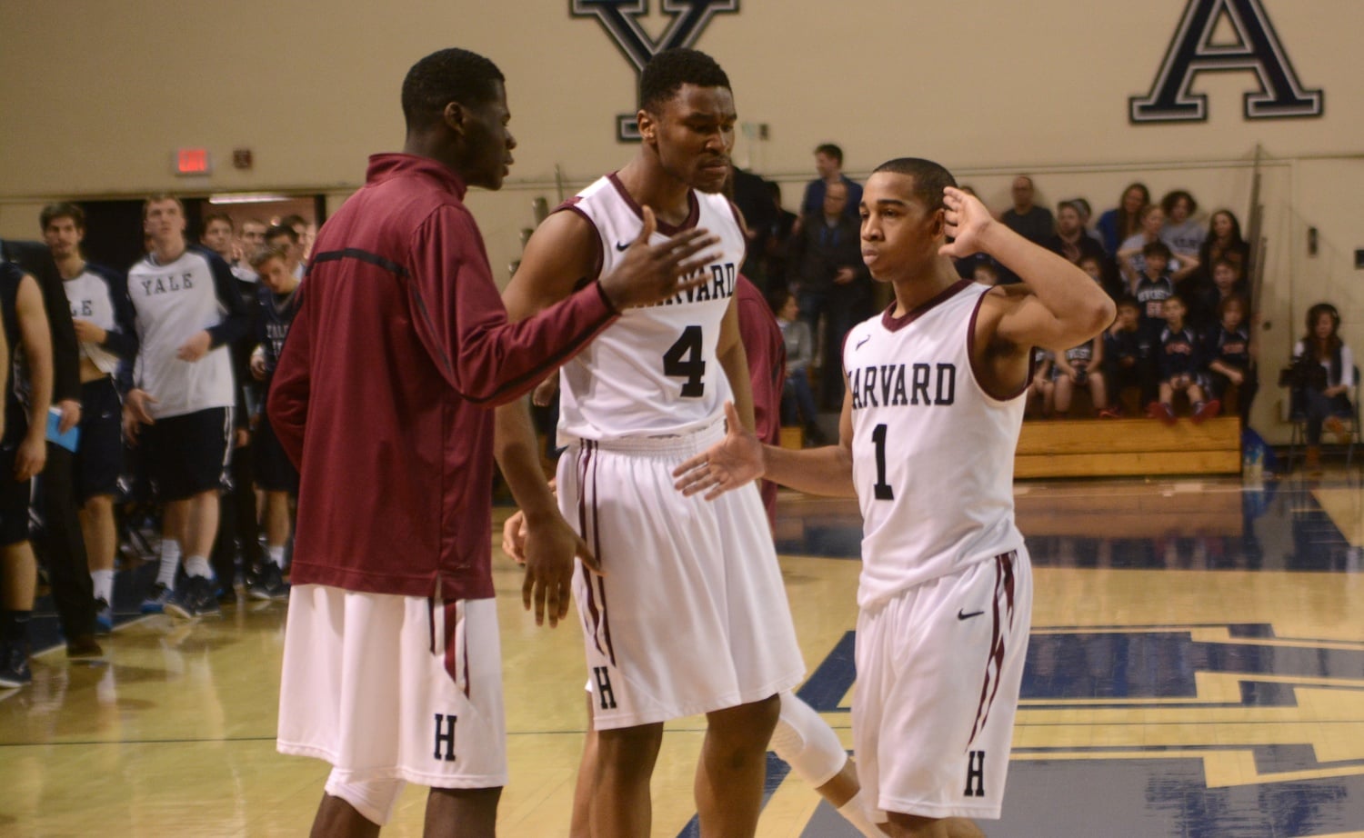 Chris E. Egi '18, left, celebrates with teammates Siyani T. Chambers '16 and Zena Edosomwan '17 after a win over Yale in 2015.