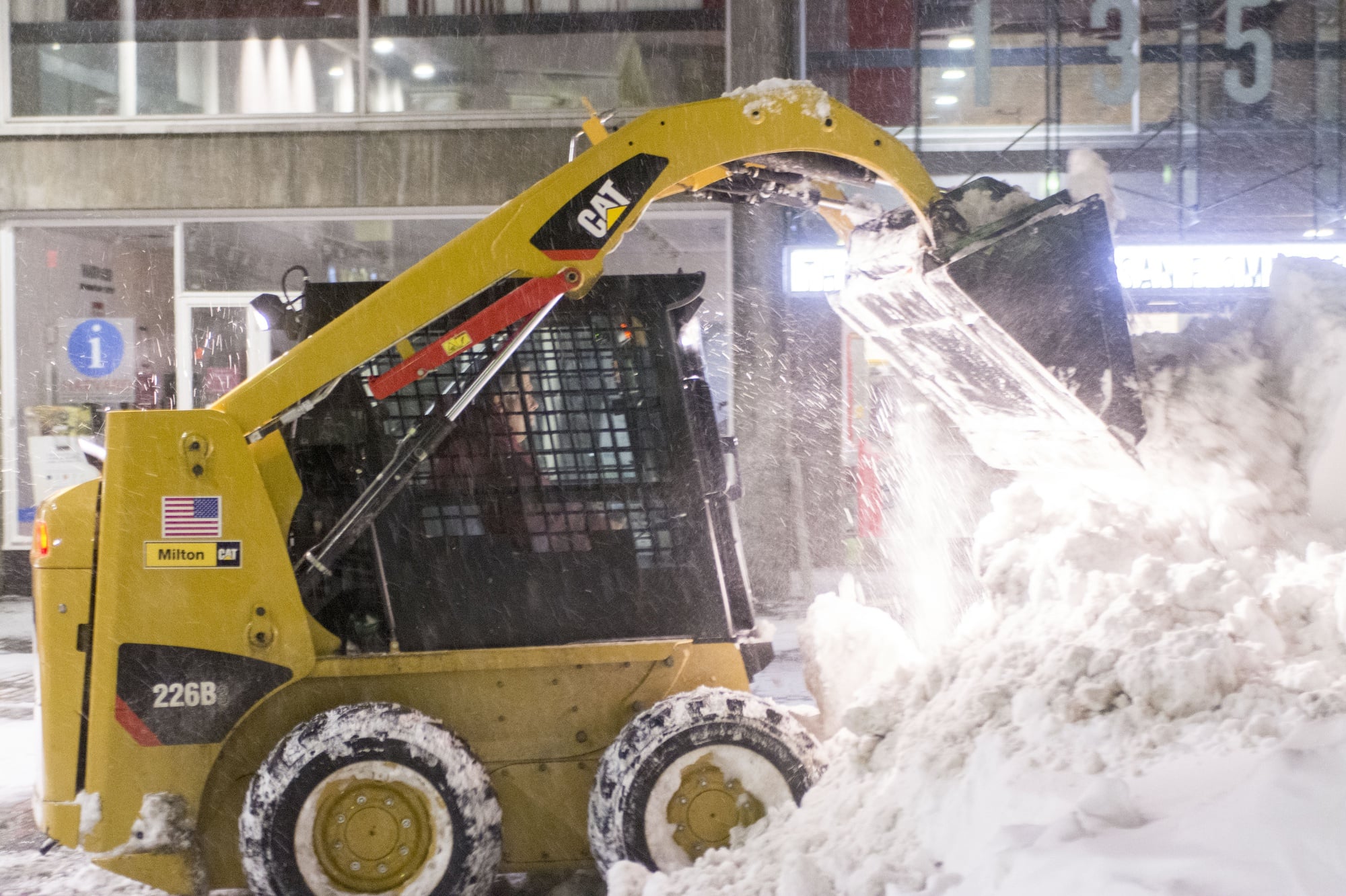 A worker clears snow from the sidewalk in front of the Smith Campus Center on Sunday night.  