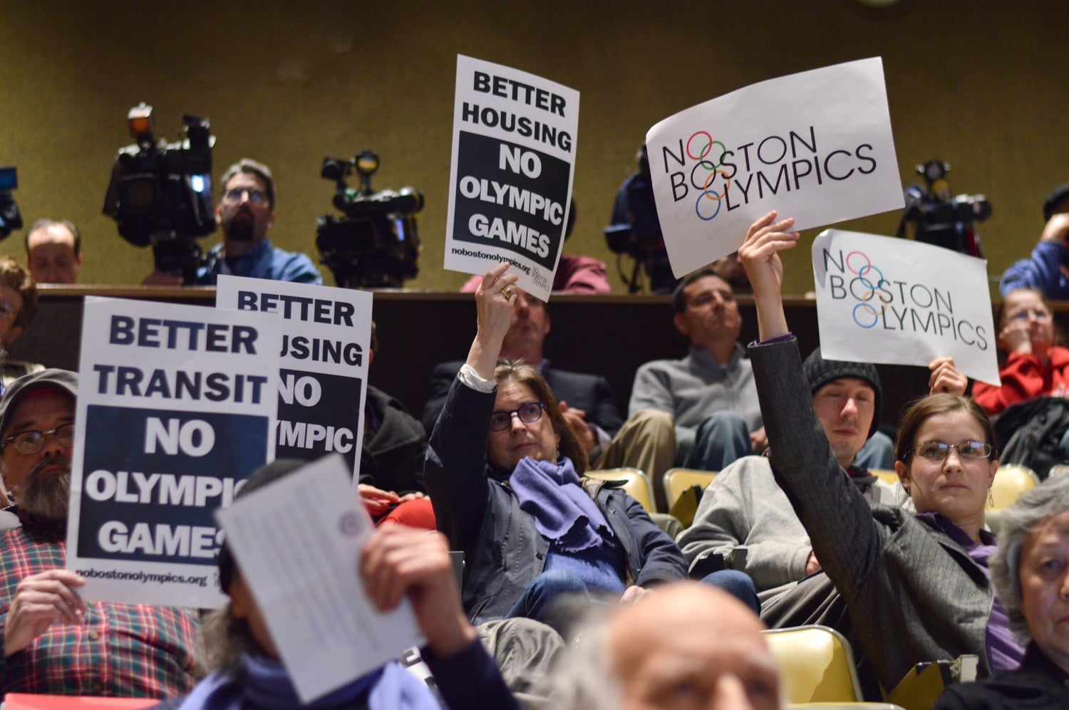 In response to a presentation from representatives of the Boston 2024 Olympic Committee, several members of the audience raise signs opposing the games Tuesday evening. The meeting, held at the Harvard Business School, was one of many planned by Olympic Boston 2024 to solicit community feedback.
