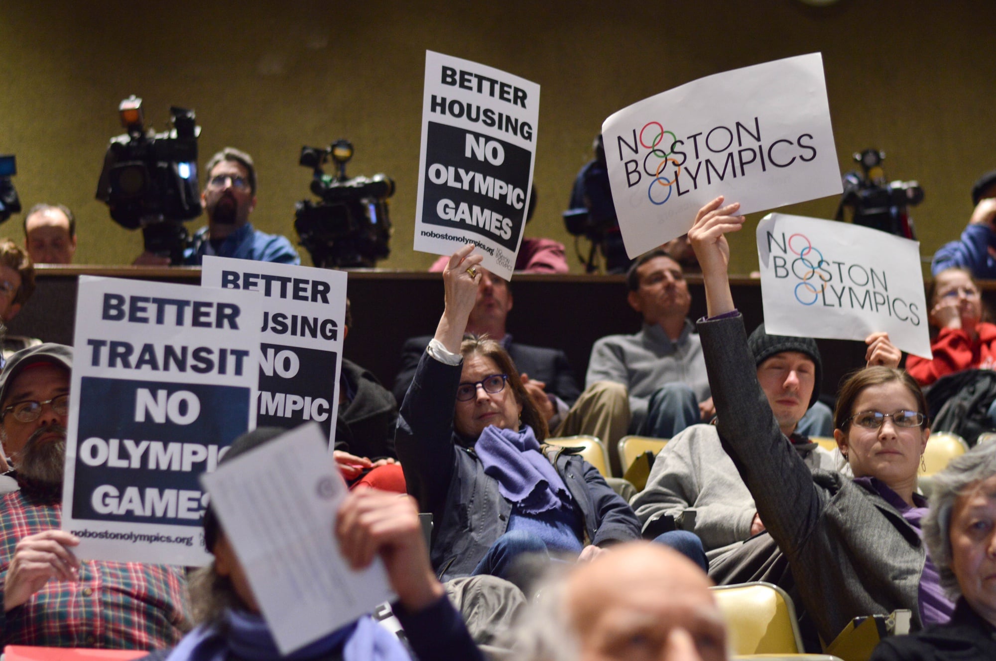 In response to a presentation from representatives of the Boston 2024 Olympic Committee, several members of the audience raise signs opposing the games Tuesday evening. The meeting, held at the Harvard Business School, was one of many planned by Olympic Boston 2024 to solicit community feedback.

