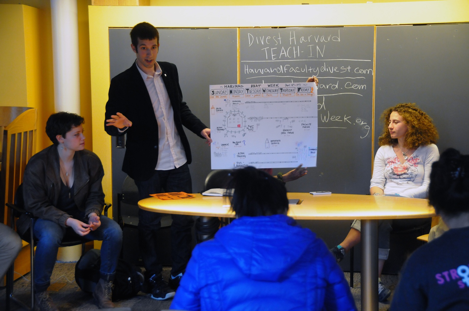 Members of Divest Harvard speak about the history of the group, which began with three students and has held active peaceful protests, fasts, and sit-ins since its conception three years ago in Ticknor Lounge on Monday evening. 