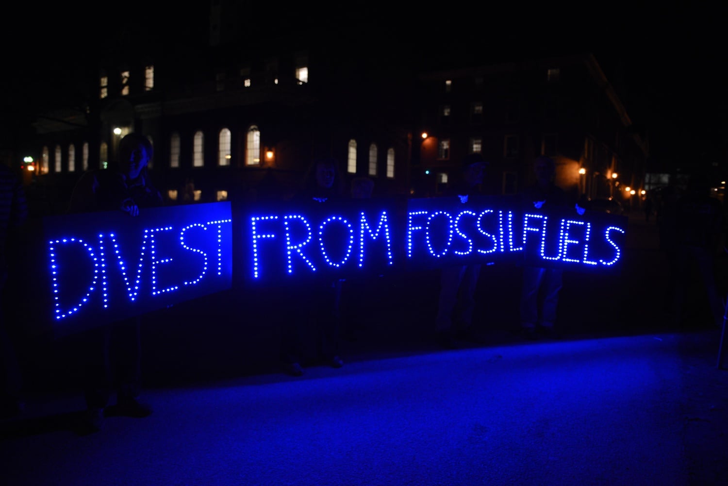 Members and supporters of activist group Divest Harvard hold signs and banners in front of Massachusetts Hall on Sunday night. The group says it plans to blockade the administrative building until Friday.