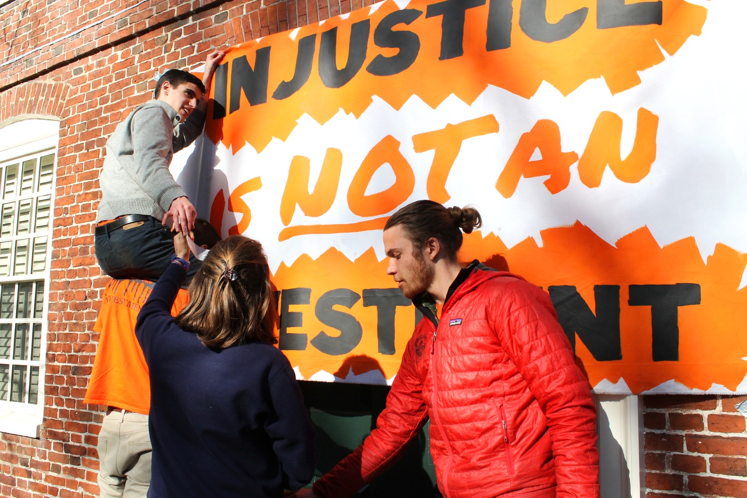 Activists of “Harvard Heat Week” begin the day by hanging orange and black posters outside of Massachusetts Hall on Monday morning. 
