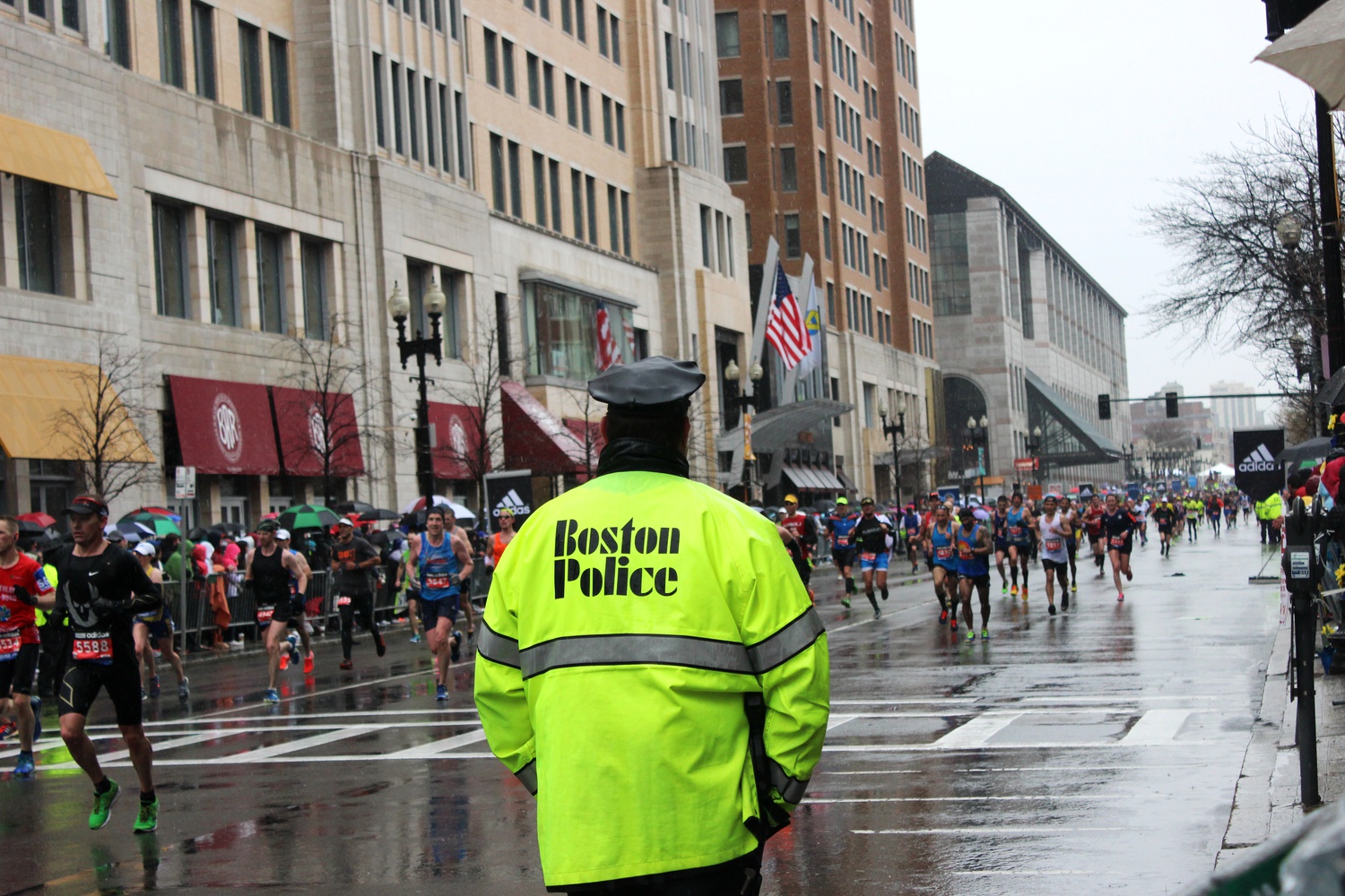 A Boston policeman looks on as runners approach the end of the race. Security was high at the race, with all bags subject to search and many policemen on standby.