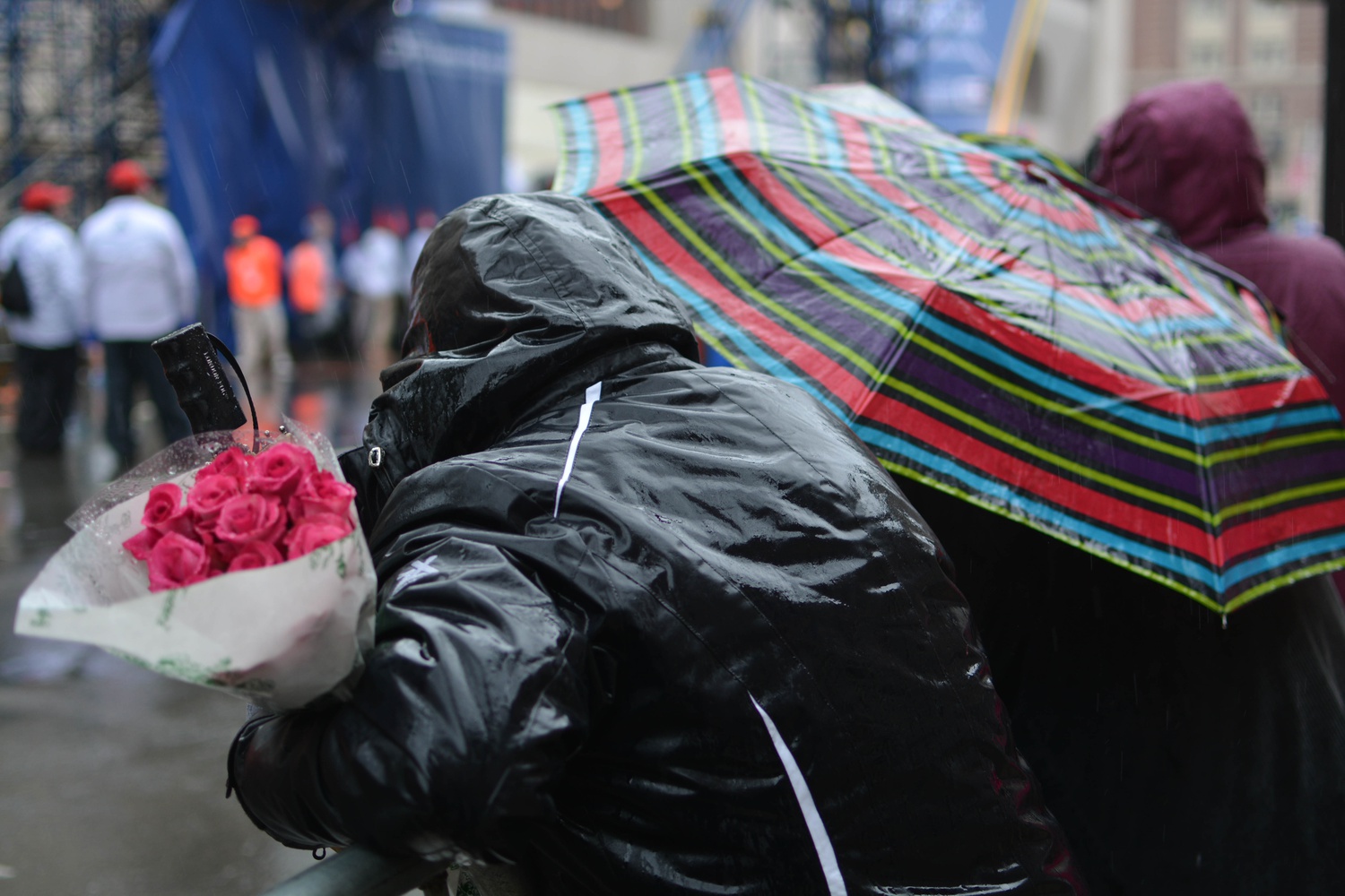 Under gray skies and rainy weather, a spectator awaits the arrival of her sister with a bouquet of flowers near the finish line.