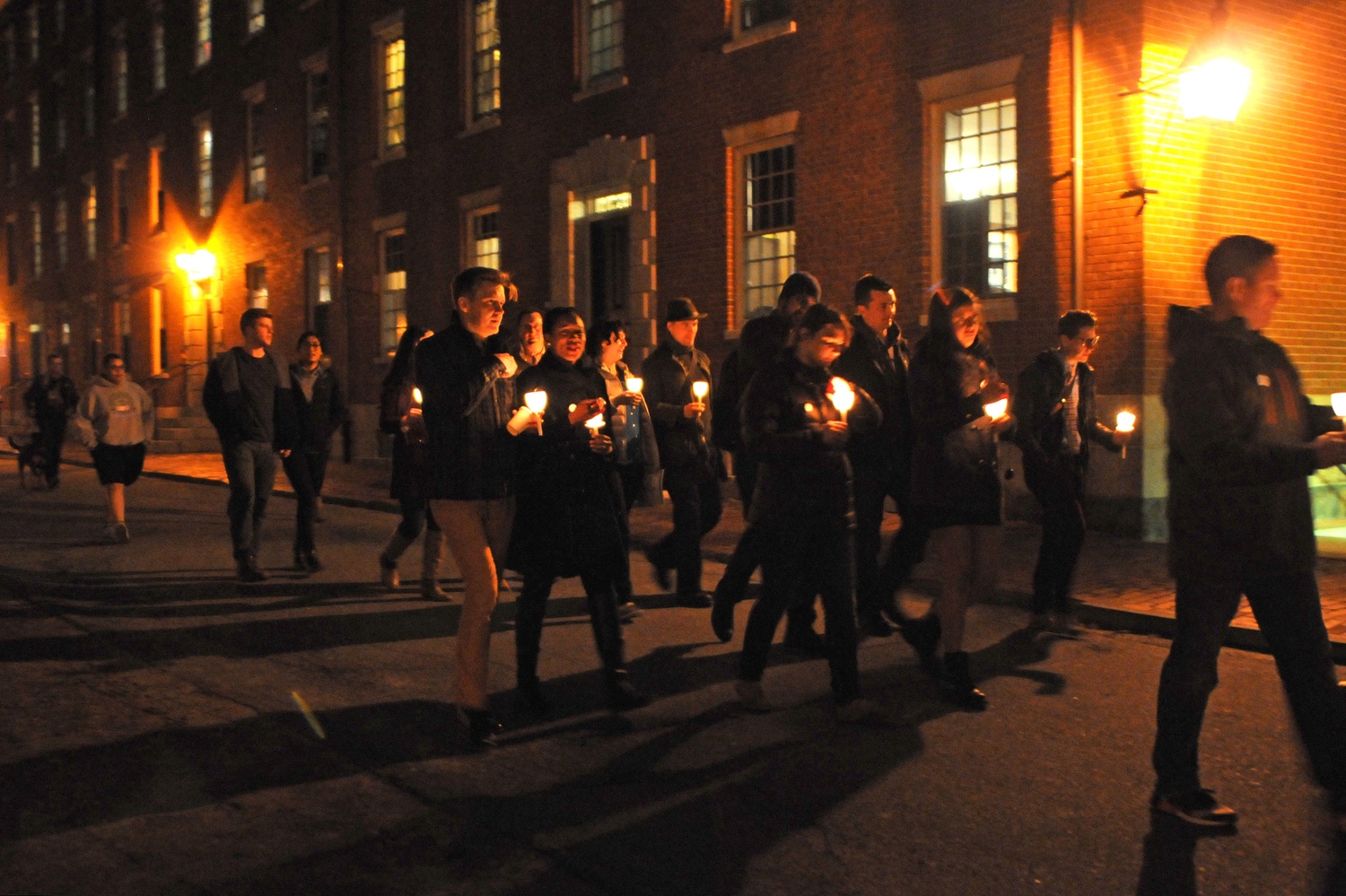 Illuminated by candles and lights from the side of Holworthy, participants in Thursday's Take Back the Night Vigil make their way through the yard in a walk to Memorial Church. 