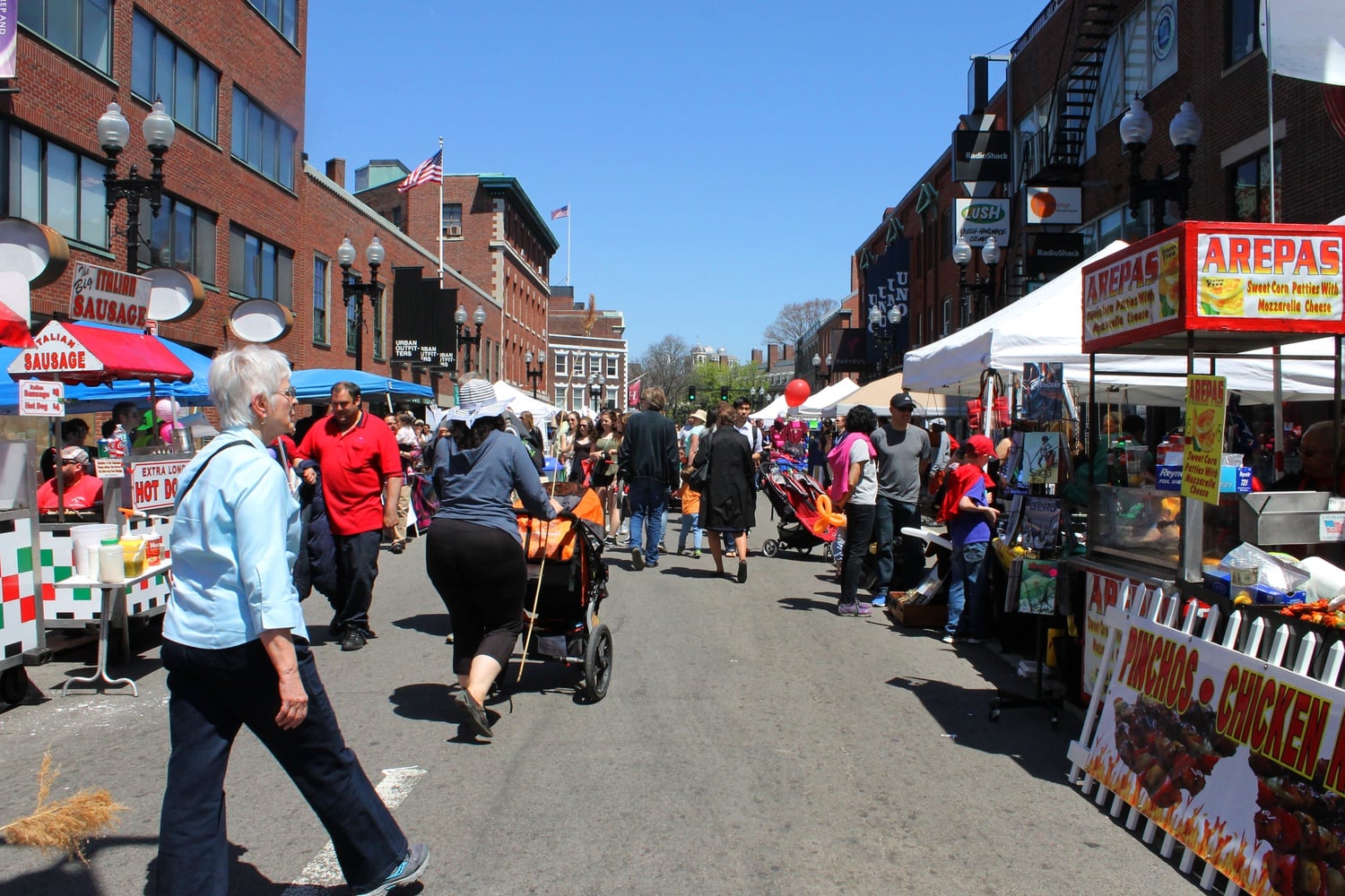 Cambridge residents and visitors enjoy food from local businesses, games, free samples, and other activities at the 32nd Annual Mayfair held in the streets of Harvard Square on Sunday afternoon. 
