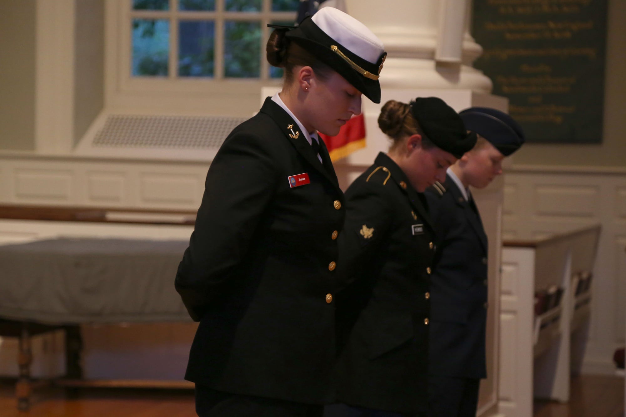 From left, Carolyn F. Pushaw ’16, Lucy F. Perkins, and Kira R. Headrick ’17 bow their heads during a 9/11 memorial service hosted by ROTC cadets and midshipmen in 2014.