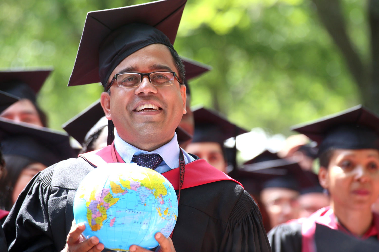 Devabrata Chakraborty holds a globe along with soon-to-be Kennedy School graduates during Commencement on May 28.