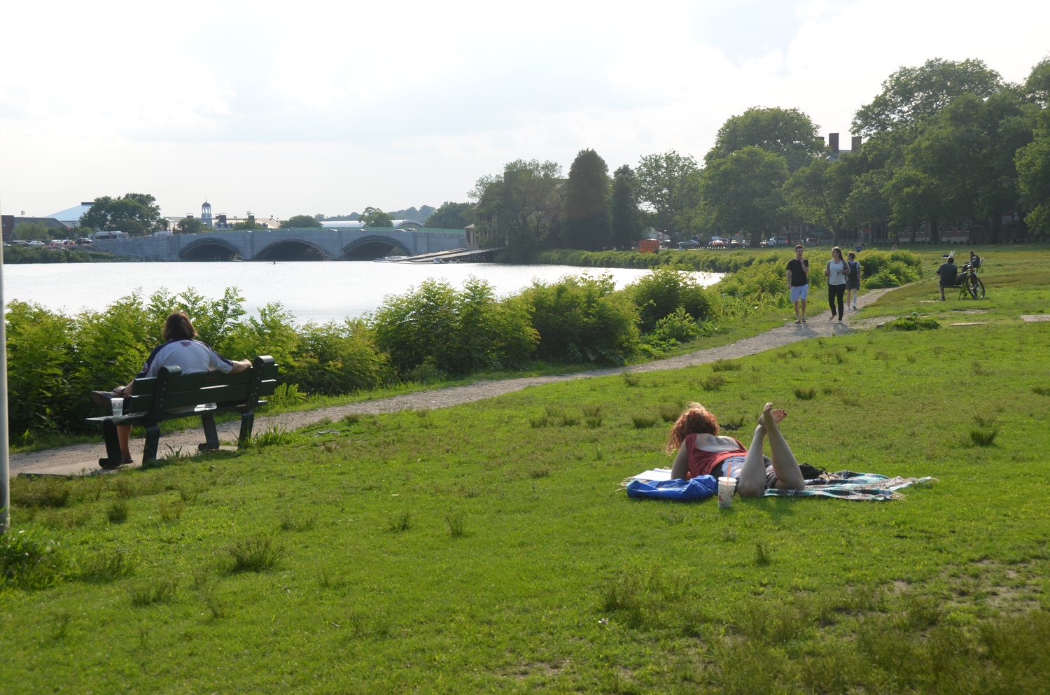 Brooke A. Bellomio, front and right, reads near the Charles River on Tuesday evening.