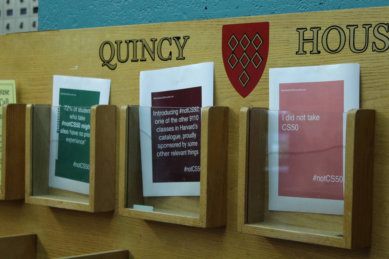 Posters for the #notCS50 campaign cover the publication rack in Quincy House. The posters appeared in houses and class buildings all over campus on Wednesday.