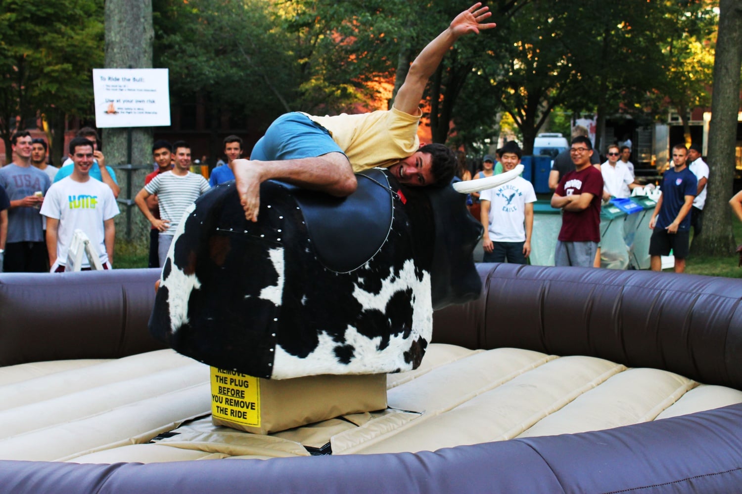 Andrew B. Soldini ’19 hangs onto the mechanical bull at Camp Harvard Monday evening in Tercentenary Theatre. 