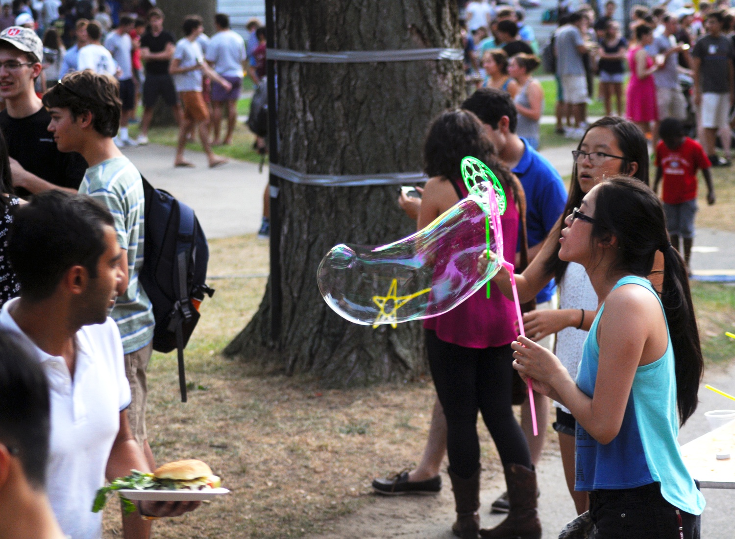 Olivia J. Chung ‘18 channels her inner child by blowing bubbles at Camp Harvard on Monday evening. 