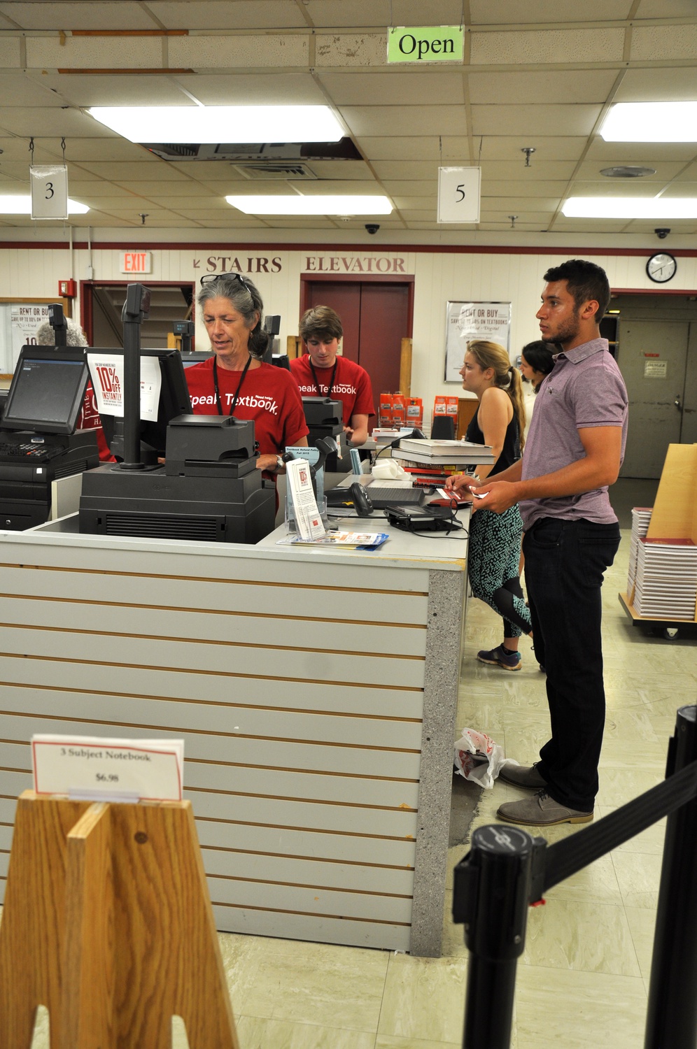 Even though students wait in long lines carrying heavy books, explained Coop employee Emily E. Glimp, “no one ever complains, no one’s ever grumpy.” Tristan T. Threatt ’18 buys coursebooks from Glimp on Thursday. 