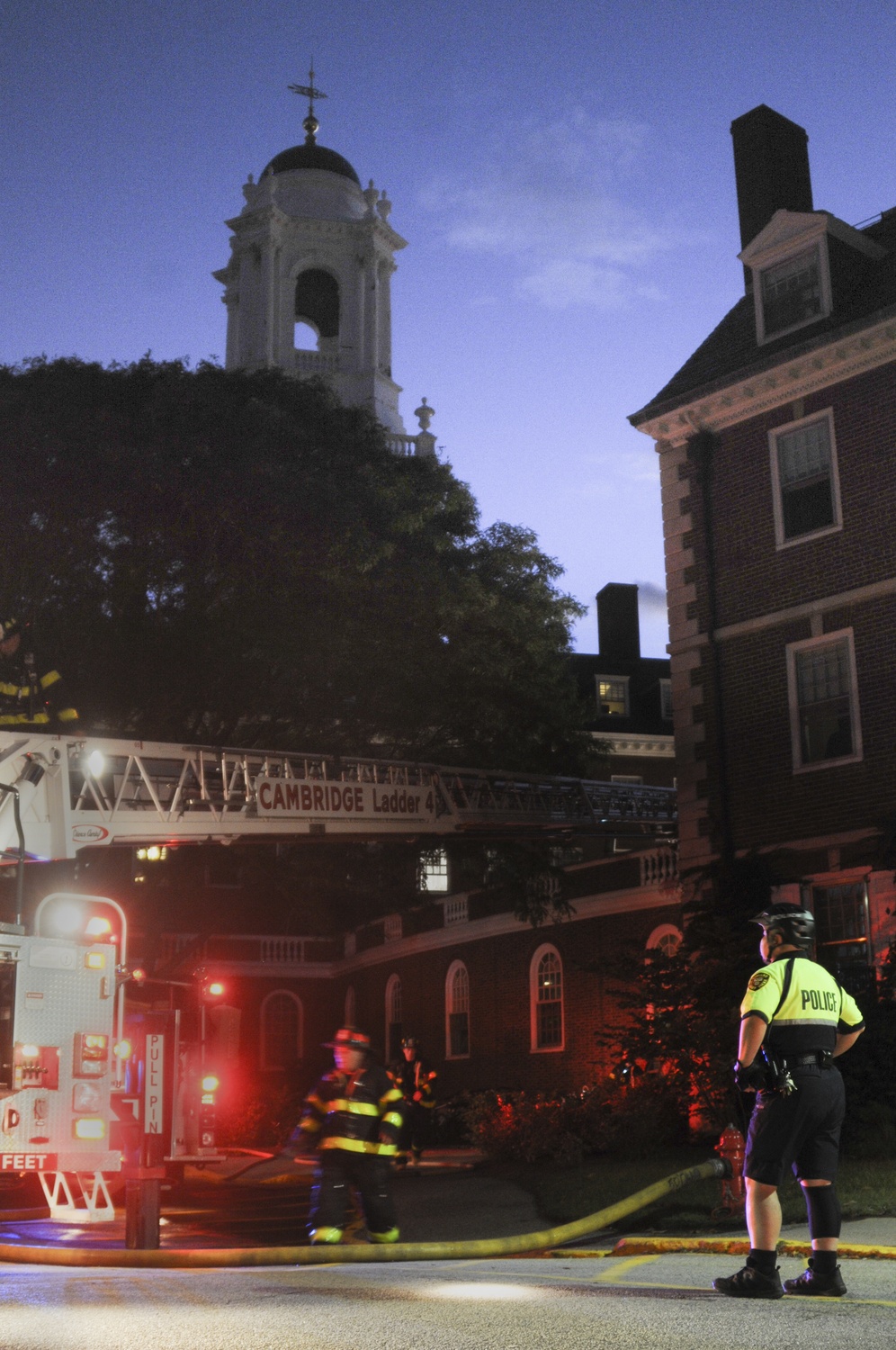A Harvard University Police Department officer stands in front of Eliot House as the Cambridge Fire Department responds to an electrical fire on Monday evening.