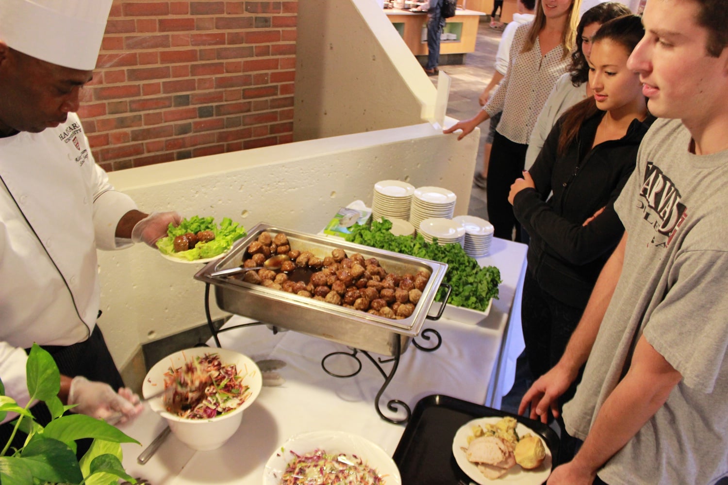 Mather House Sous Chef Alex Drumm serves his Pork and Beef Thai Meatballs with a Mint Slaw as part of Thursday’s Community Dinner. HUDS partnered with the Harvard Art Museums to have house chefs design a themed entrée corresponding with the current special exhibition: Corita Kent and the Language of Pop. The event drew its inspiration from Kent’s 1960s-era pop art prints, now on exhibit in the Harvard Art Museums.