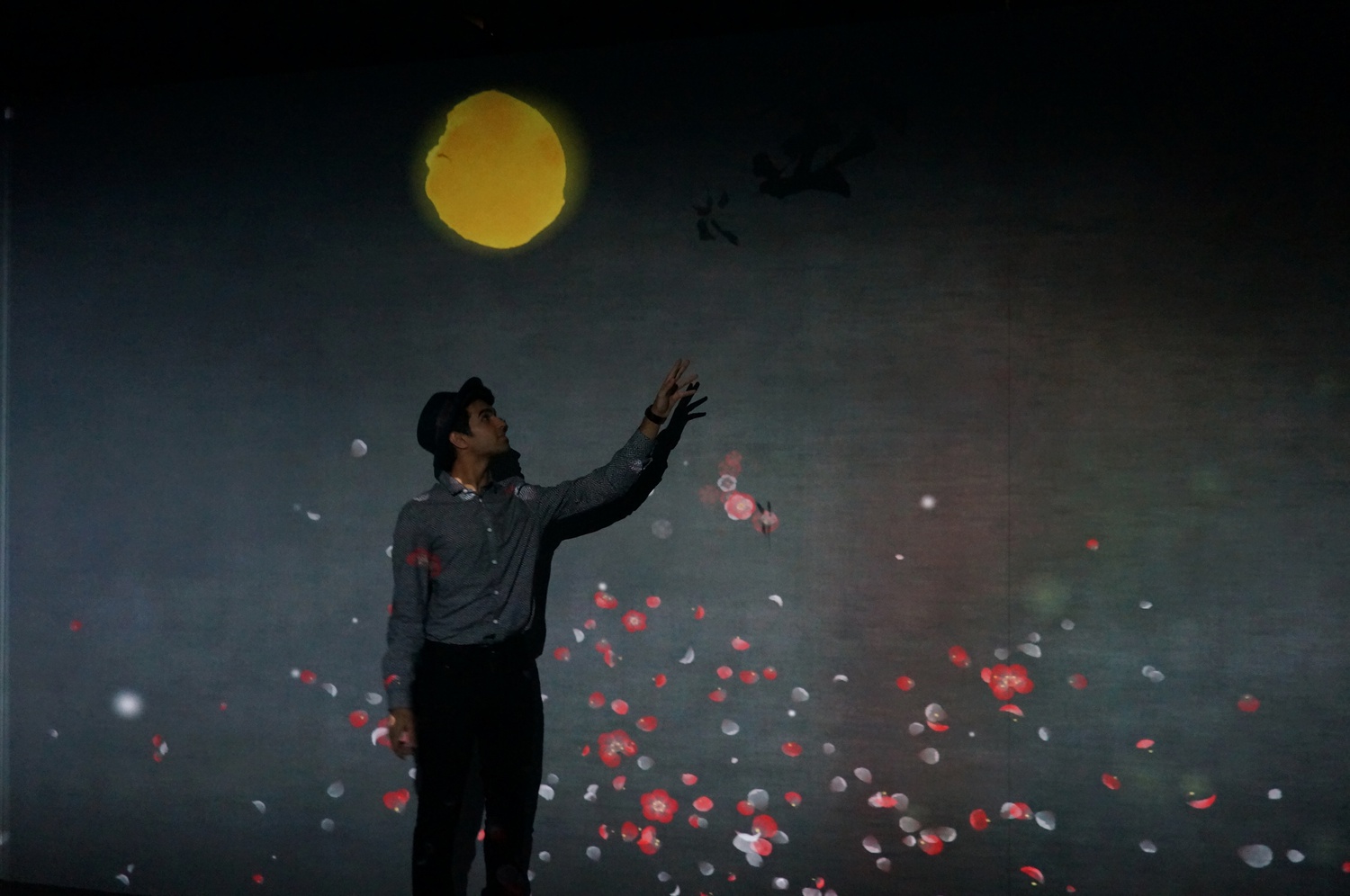 Saad Amer ’16  touches the Chinese and Japanese characters on the walls of the exhibit, which interact with images generated from other characters to create unique, evolving animations.