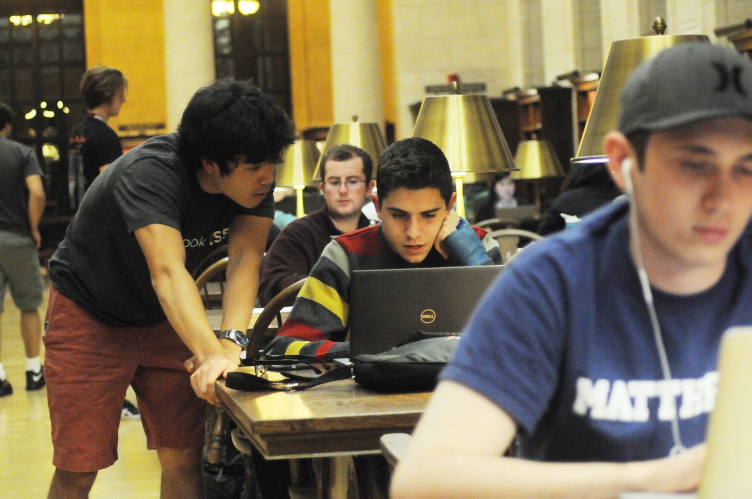 Jordan H. Hayashi, left, a teaching fellow for CS50, assists a student during CS50 office hours in Widener Library on Monday evening. 