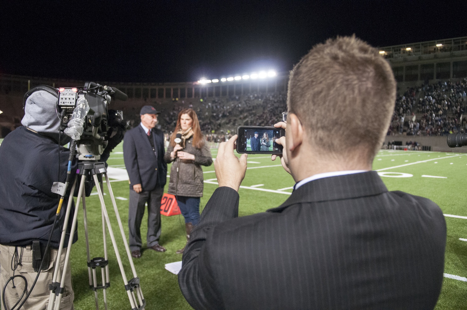 Tim Williamson, right, films on his phone while a Fox College Sports reporter interviews Director of Athletics Bob Scalise during halftime of the Harvard-Brown football game in late September.