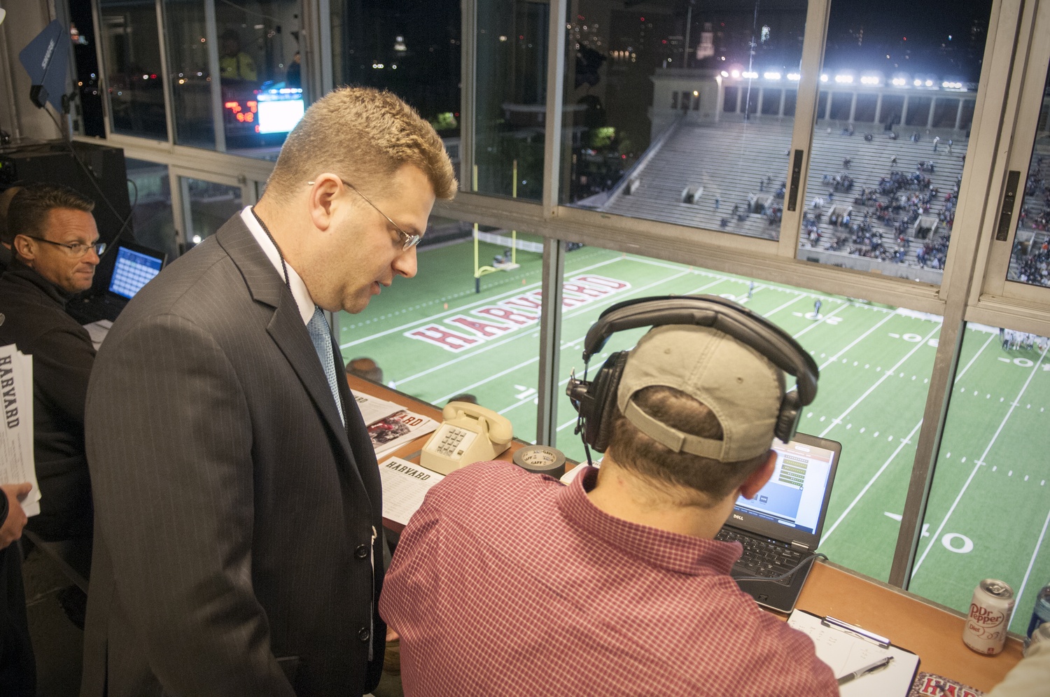 Harvard's Director of Athletic Communications, Timothy J. Williamson, works the press box during a football game this fall. 
