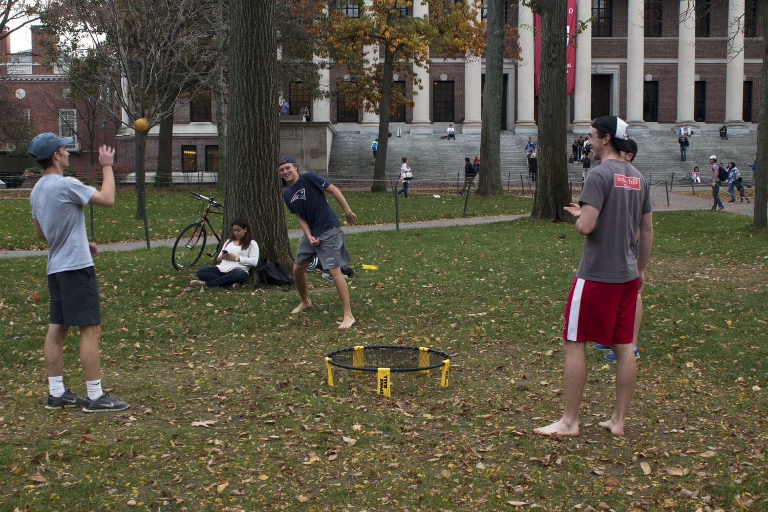 Students taking advantage of the warm weather play spike ball in Harvard Yard.