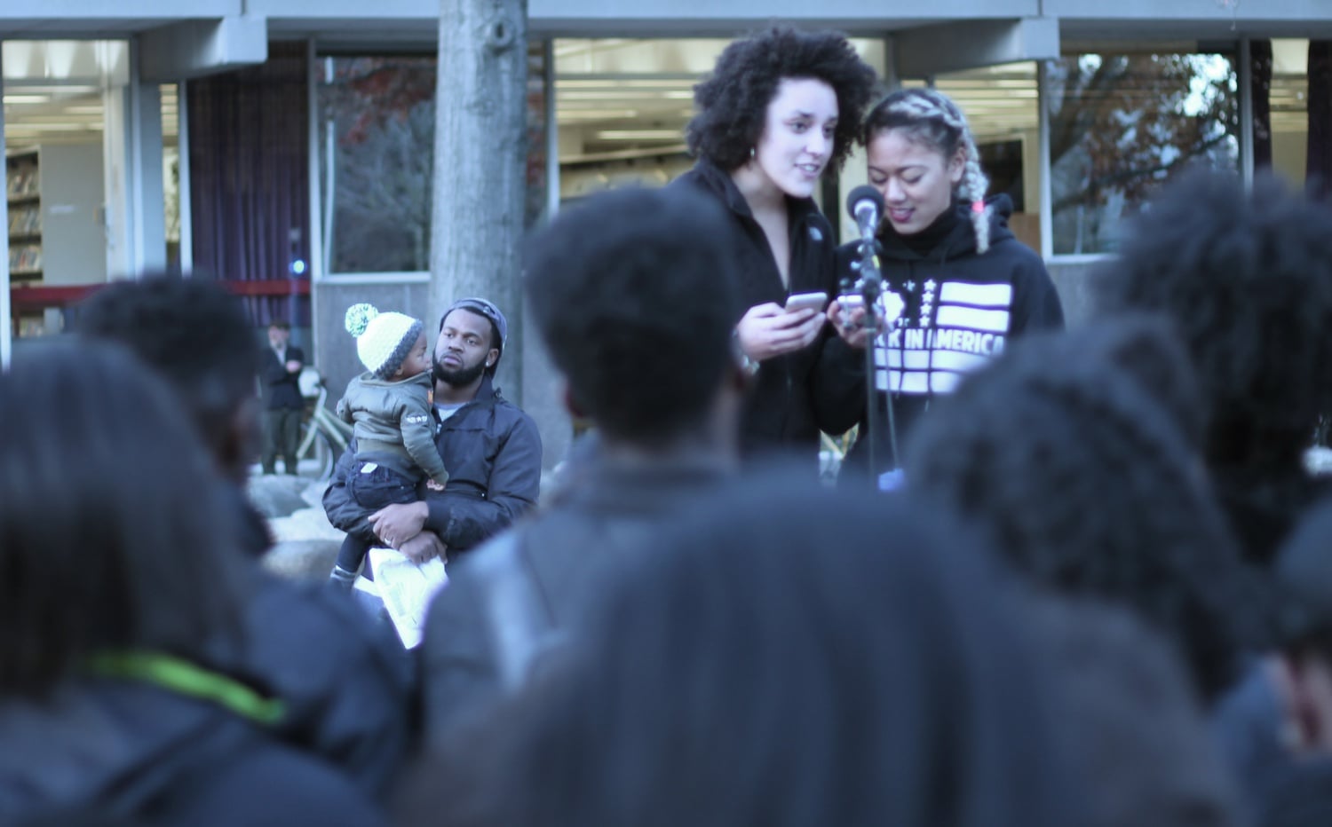 Bystanders listen as Kimiko M. Matsuda-Lawrence ‘16 and Jenny A. Gathright ‘16 perform a spoken-word poetry piece about their experiences as black women at Harvard. Students performed and demonstrated at the Science Center Plaza before joining Tufts at Porter Square.