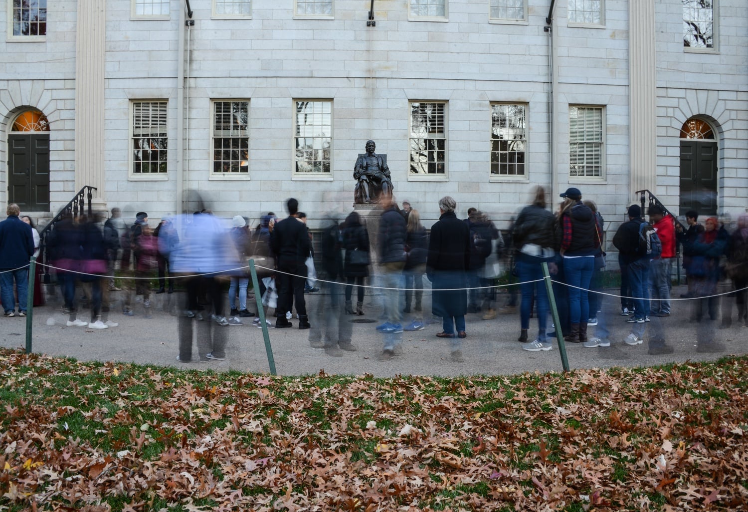 A stream of tourists passes John Harvard Statue, a famous tourist destination of the campus and Boston itself. The statue is the third most photographed in the US behind the Statue of Liberty and the Lincoln Memorial.