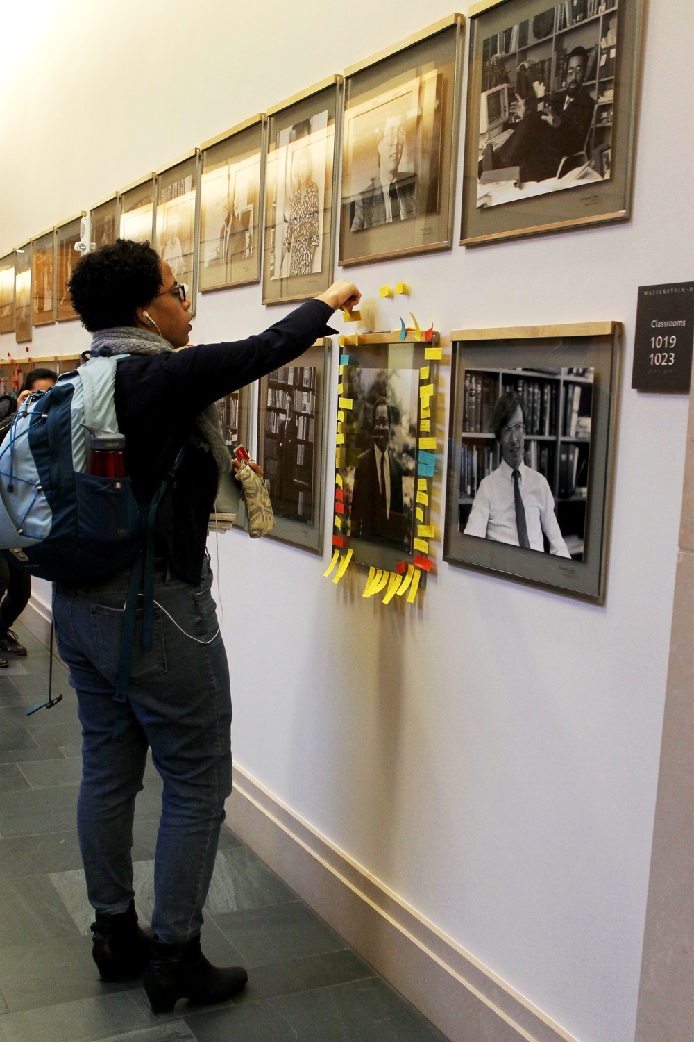 Tori Anderson, a third-year Harvard Law School student, adds a sticky note to the portrait of a black Law School professor on Thursday in a motion of support for the faculty.